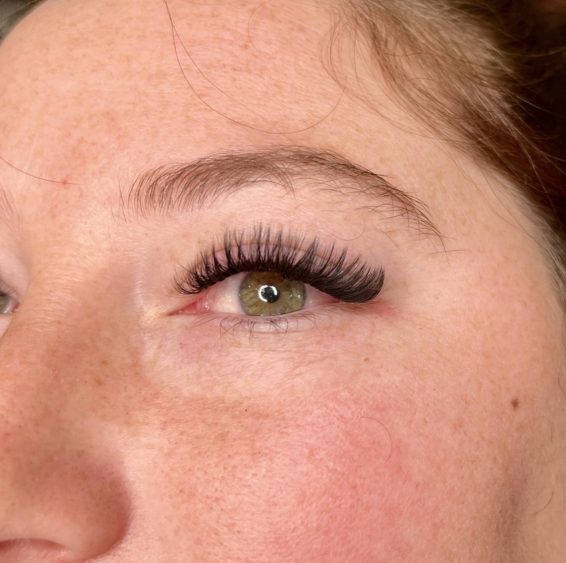 Close-up of a person's eye with makeup, showcasing the upper eyelid, eyelashes, and eyelashes with mascara.
