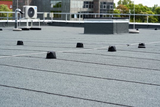 View of a flat rooftop with mounted wind sensors or antennae, and a building in the background.