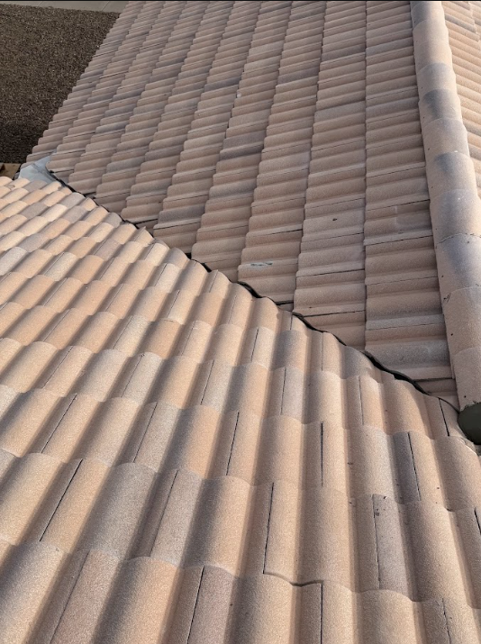 Close-up view of overlapping beige clay roof tiles on a sloped roof.