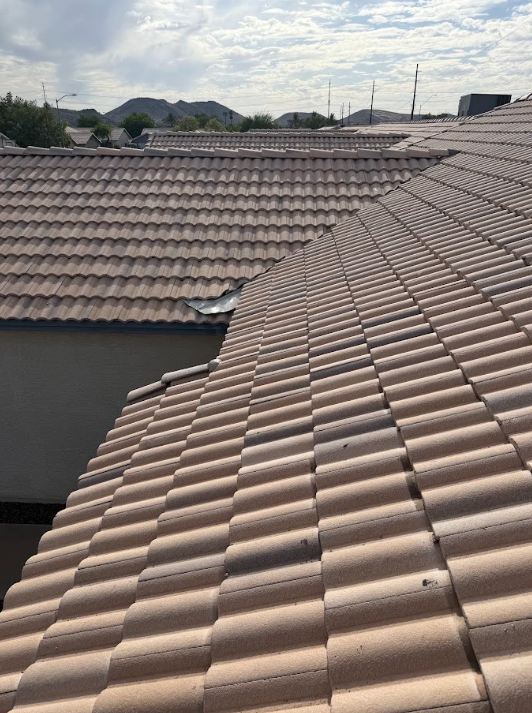View of multiple rooftops with brown tile shingles under a partly cloudy sky in a residential area.