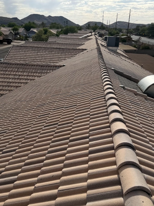 View of rooftops with clay tiles and mountain landscape in the distance.