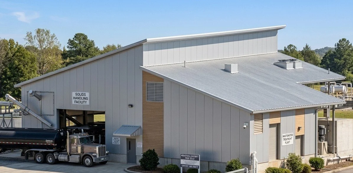 Industrial facility with a metal building labeled 'Solids Handling Facility' and 'Masterfiber Treatrate Plant', a large truck parked outside, surrounded by trees.
