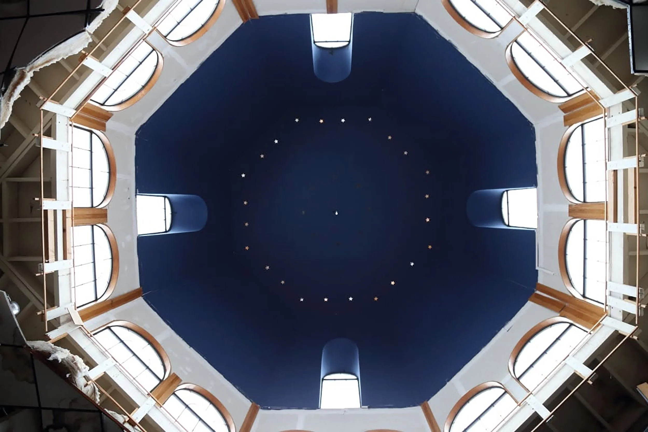 Interior view of a spiral staircase from below, with a dark blue ceiling and small star-shaped lights.