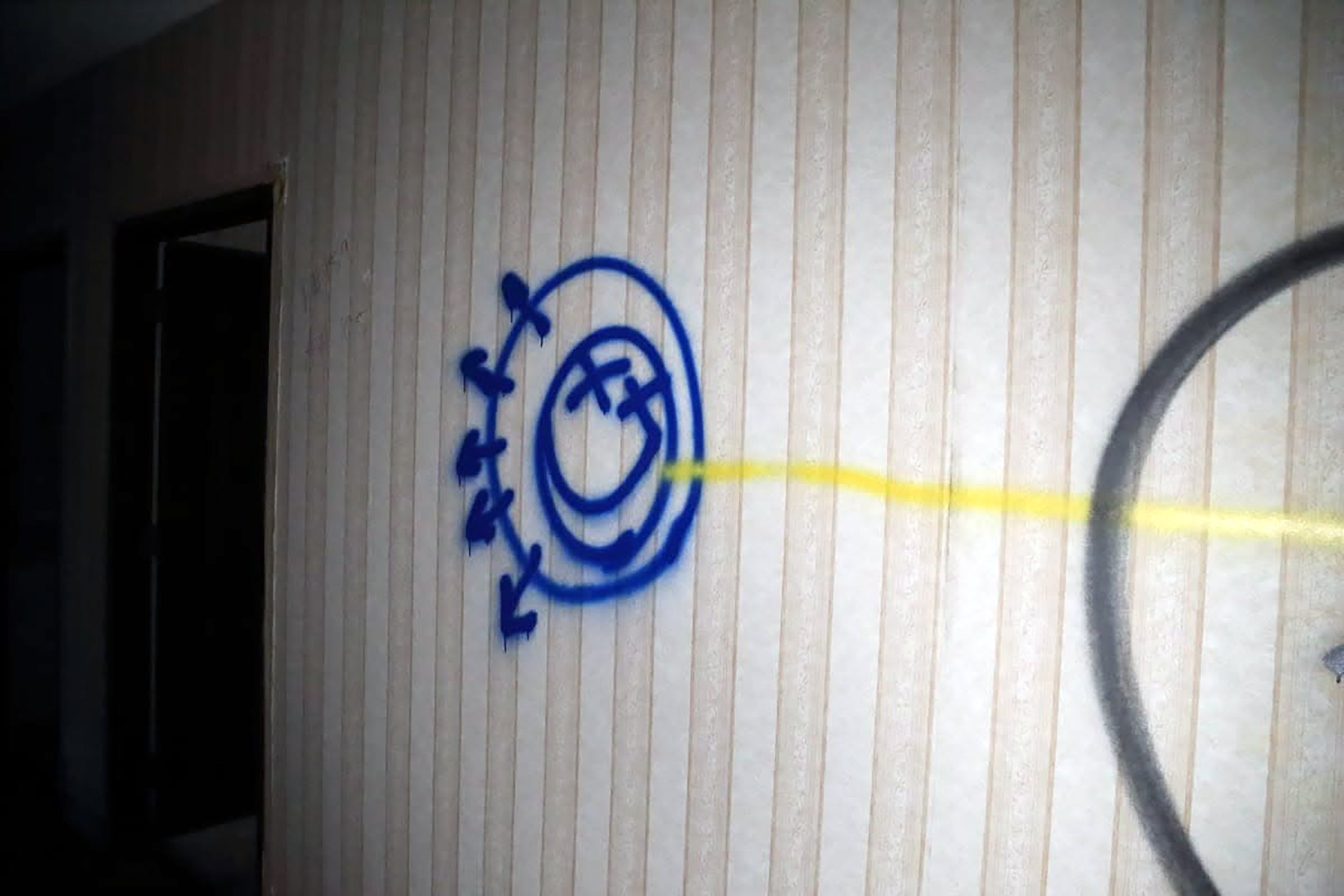 Colorful drawing on a lined piece of paper featuring a blue spiral with dots around it, with a yellow line extending from the spiral to the right side of the page. The page has vertical lines and is on a dark surface.