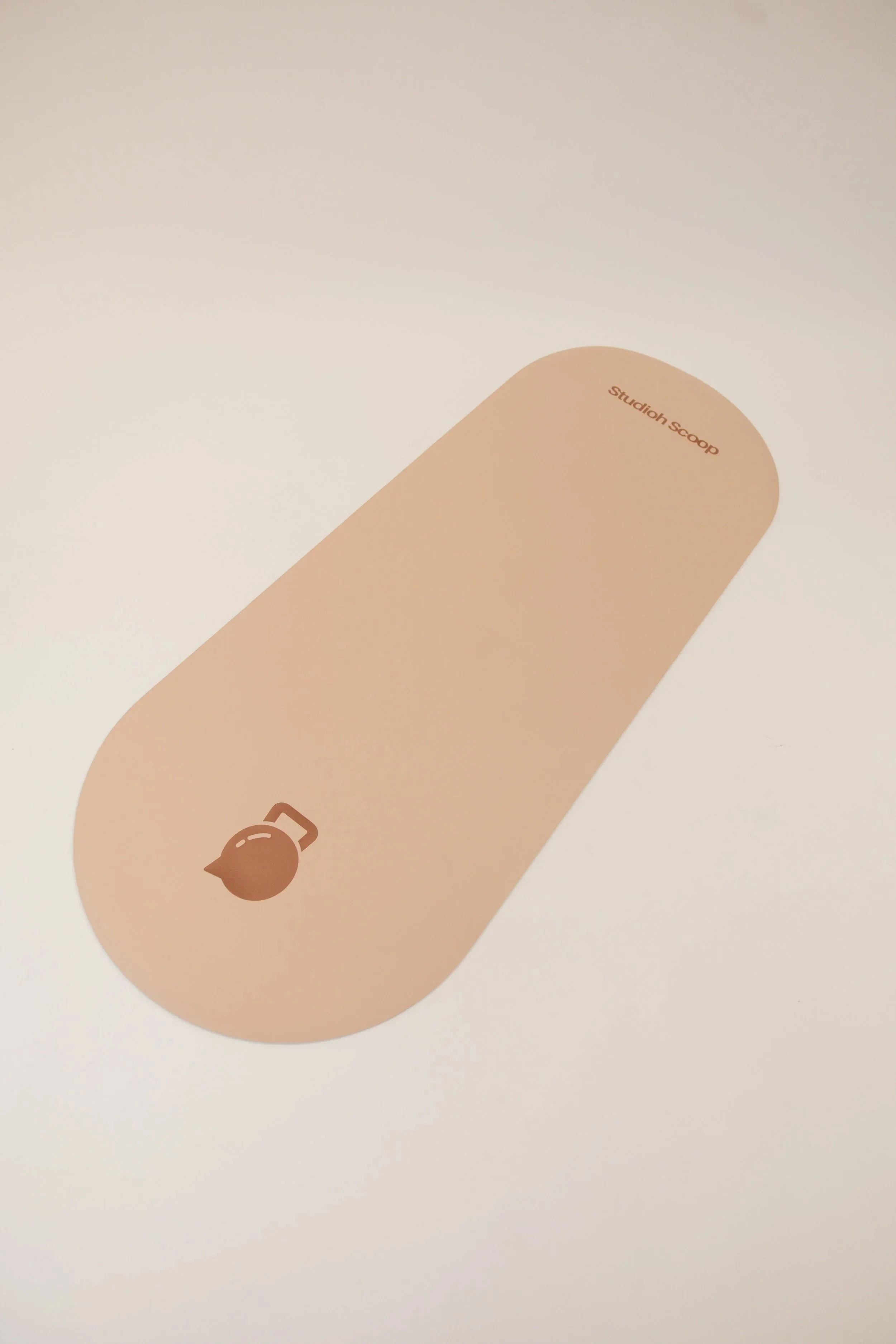 Close-up of a beige object with the text 'Studioh Scoop' on the top and a small icon of a scoop below, placed on a white surface.