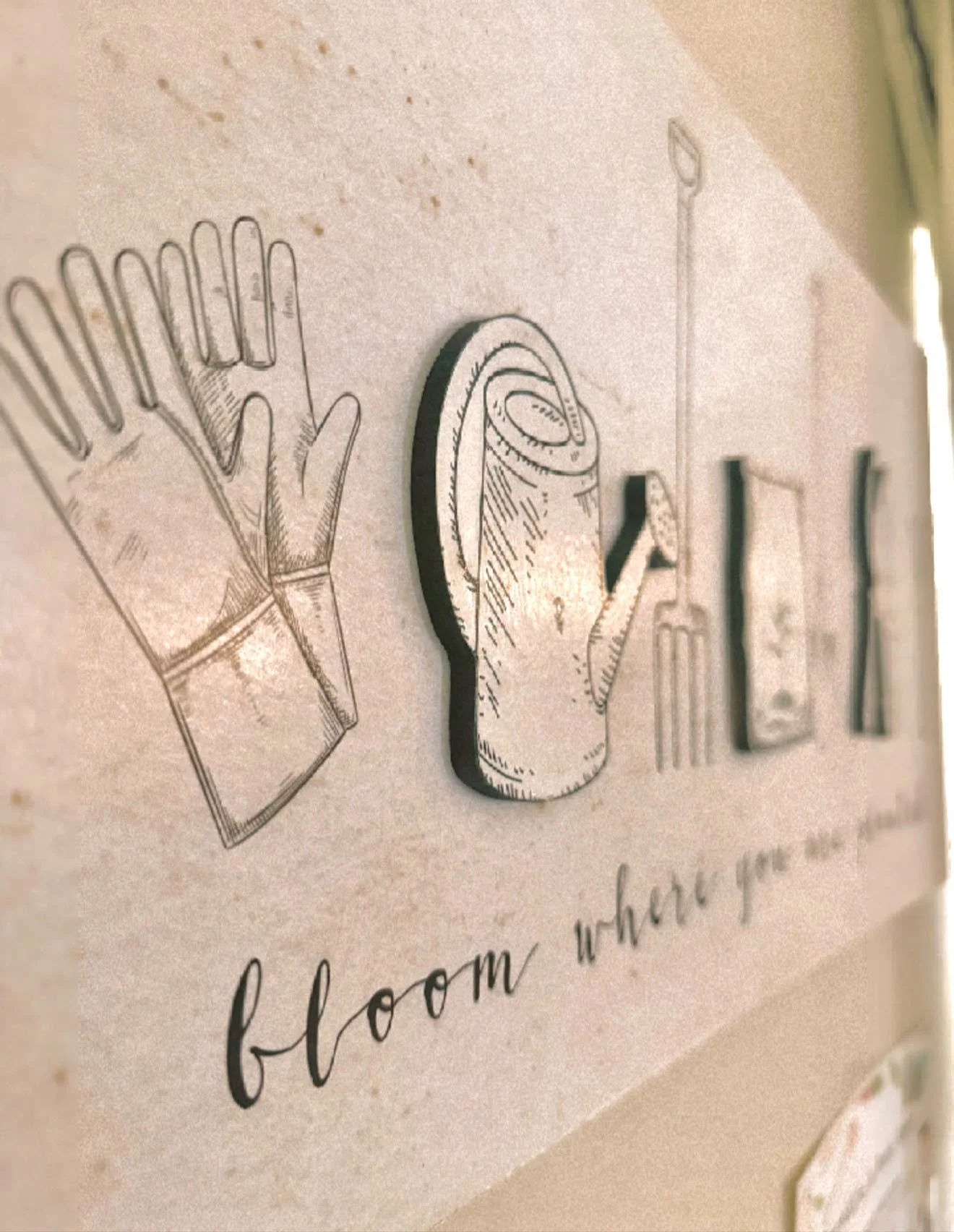 Close-up of an embroidered decorative sign featuring illustrations of a hand, a roll of toilet paper, and a hand sanitizer bottle with the phrase "from where you" written underneath.