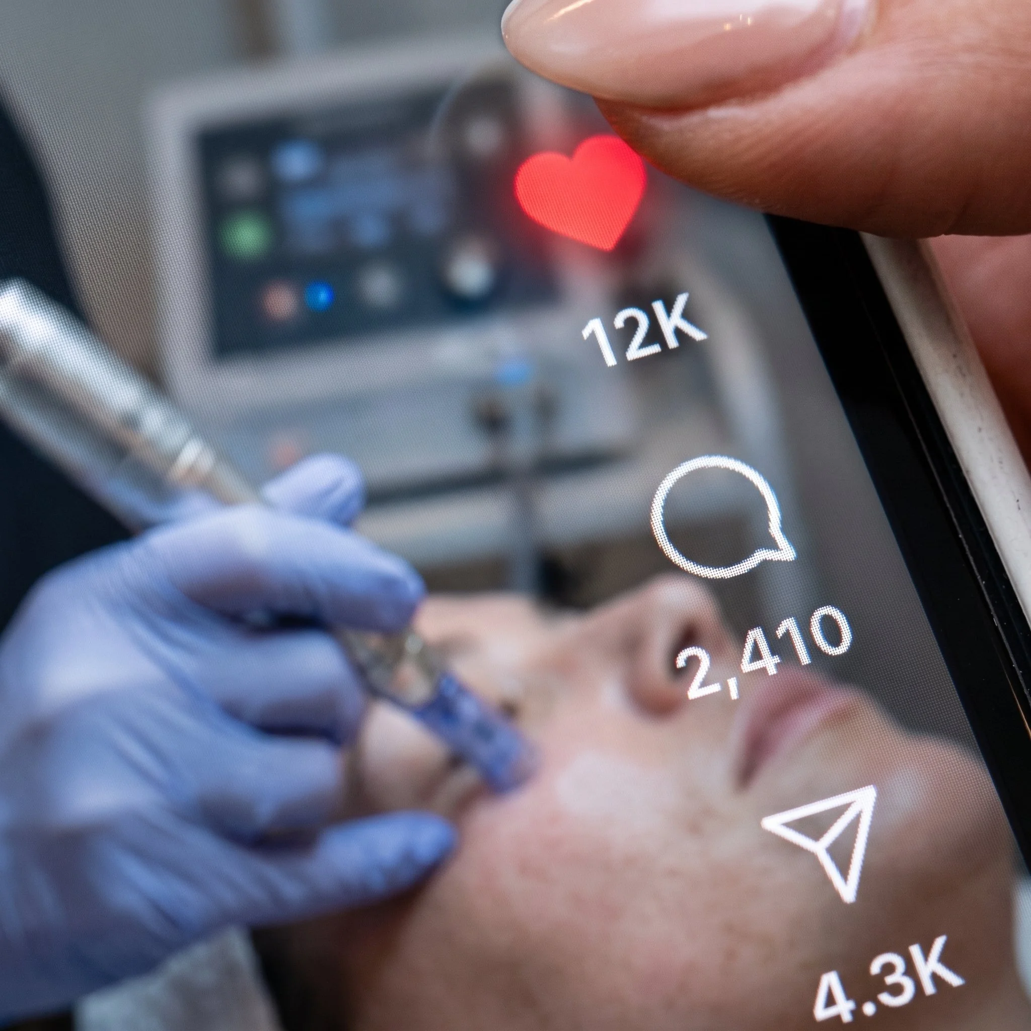 Close-up of a smartphone screen showing a red heart emoji and a message count of 12.4K, with a finger partially visible near the edge of the screen.