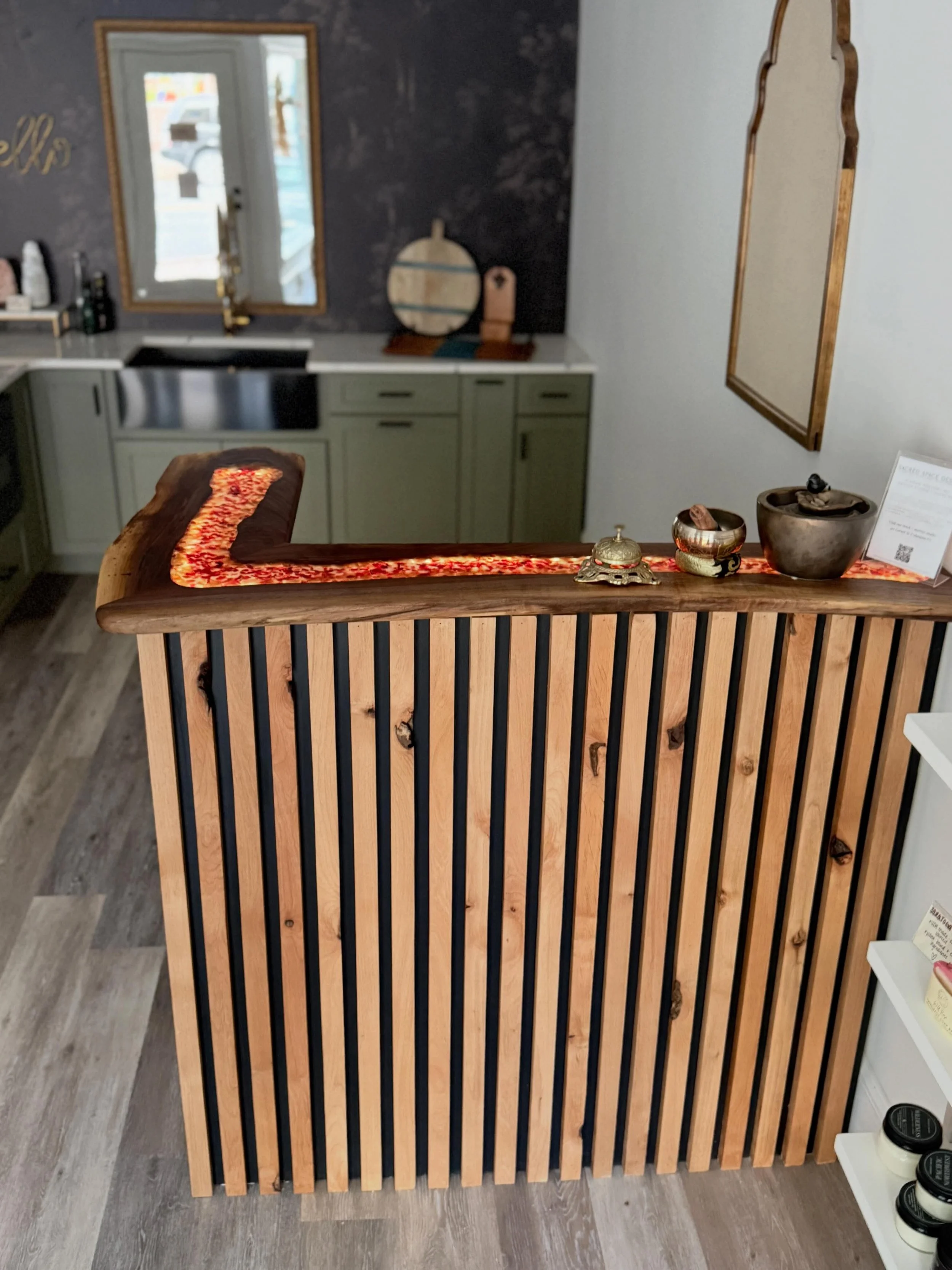 A wooden slat room divider with black vertical bars on a light wooden frame, placed on a light-colored wooden floor.