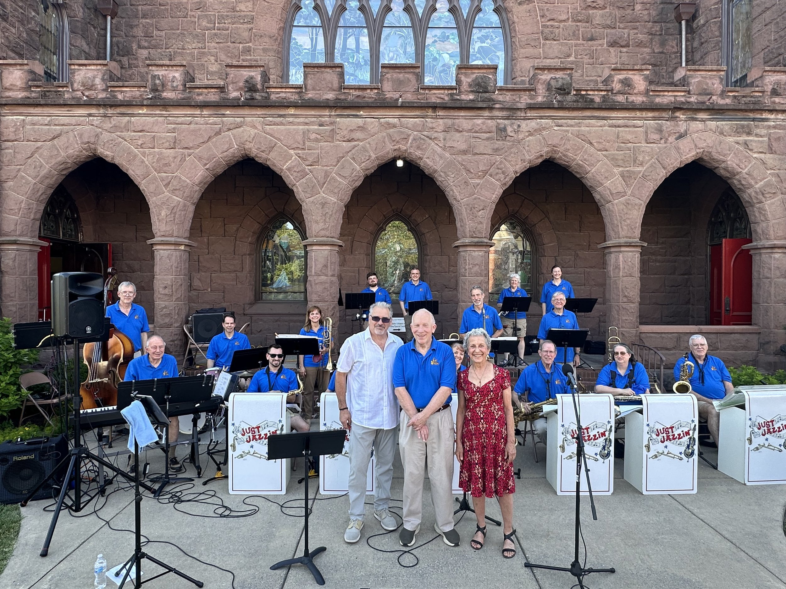 Group of musicians in blue shirts standing behind music stands with