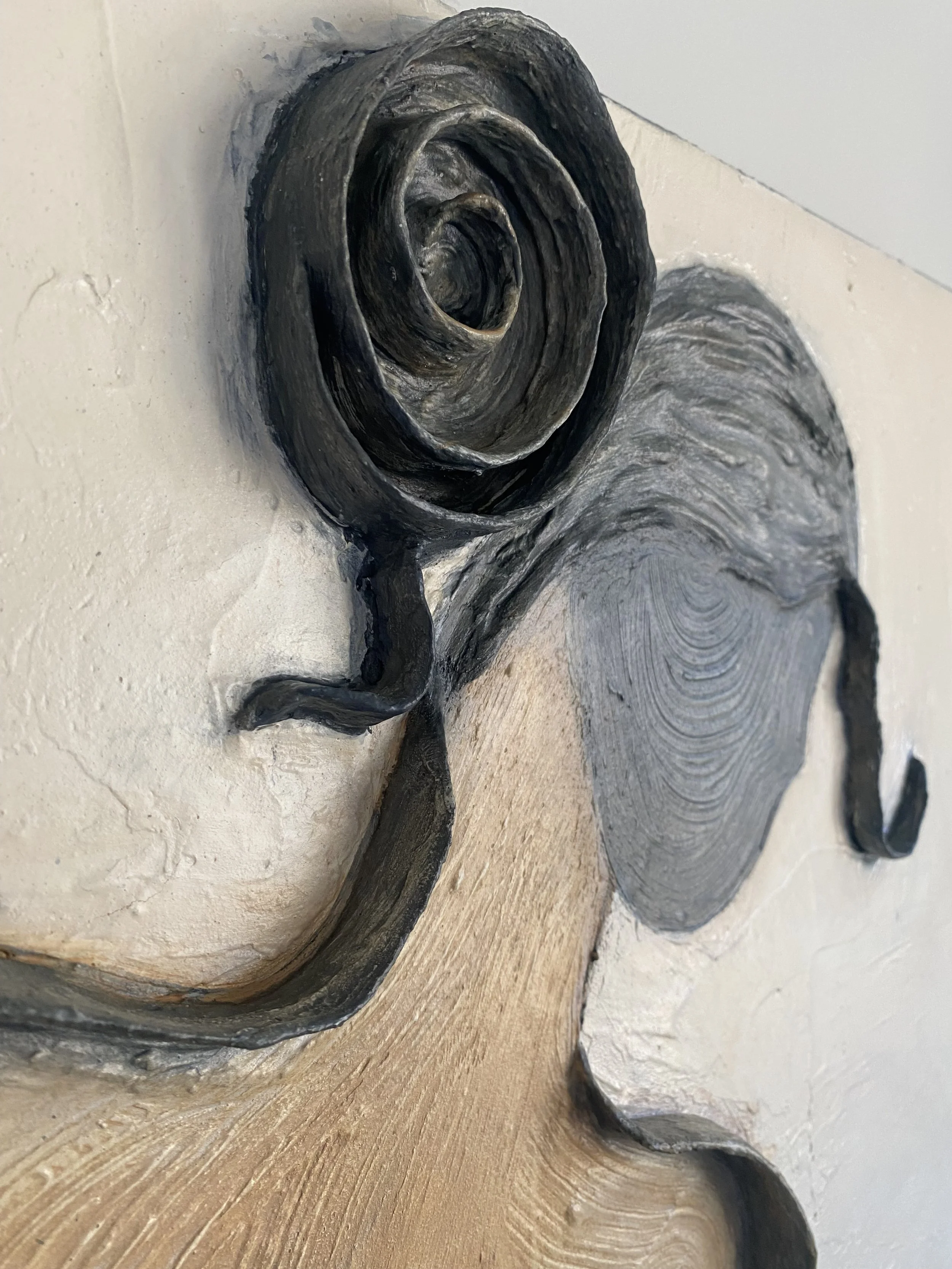 Close-up of a carved wooden sculpture featuring a spiral shell-like form and textured dark details
