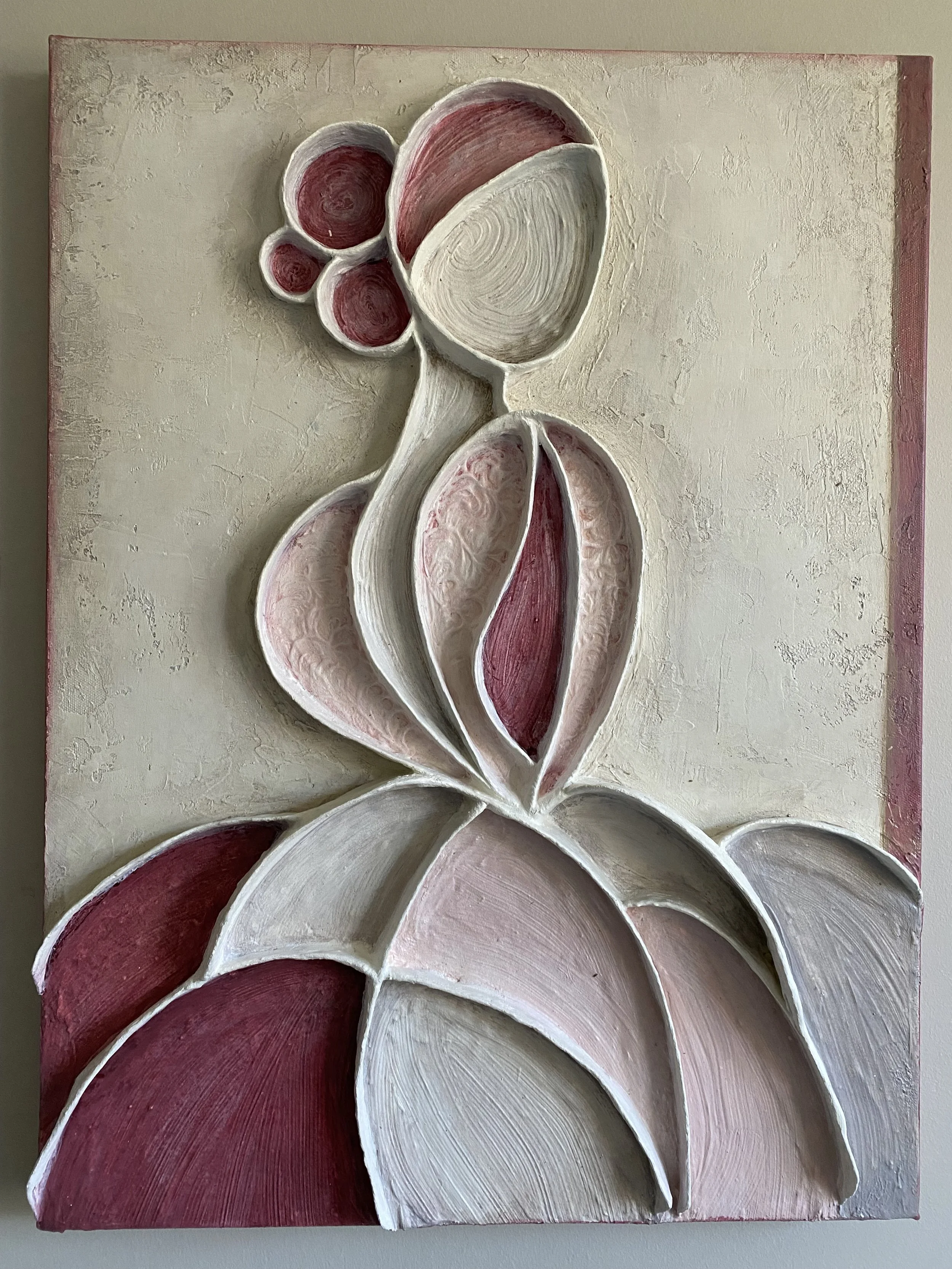Close-up of a textured floral wall relief featuring layered pink, burgundy, and white petals on a neutral background
