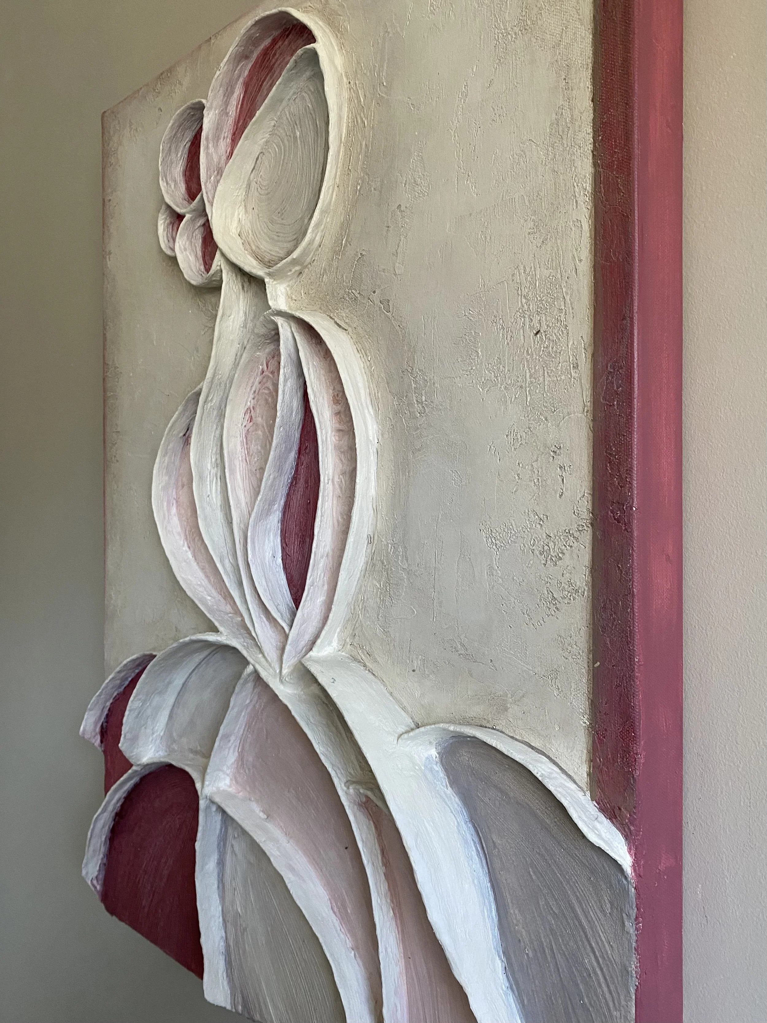 Close-up of an ornate white and pink floral plaster wall relief beside red architectural trim
