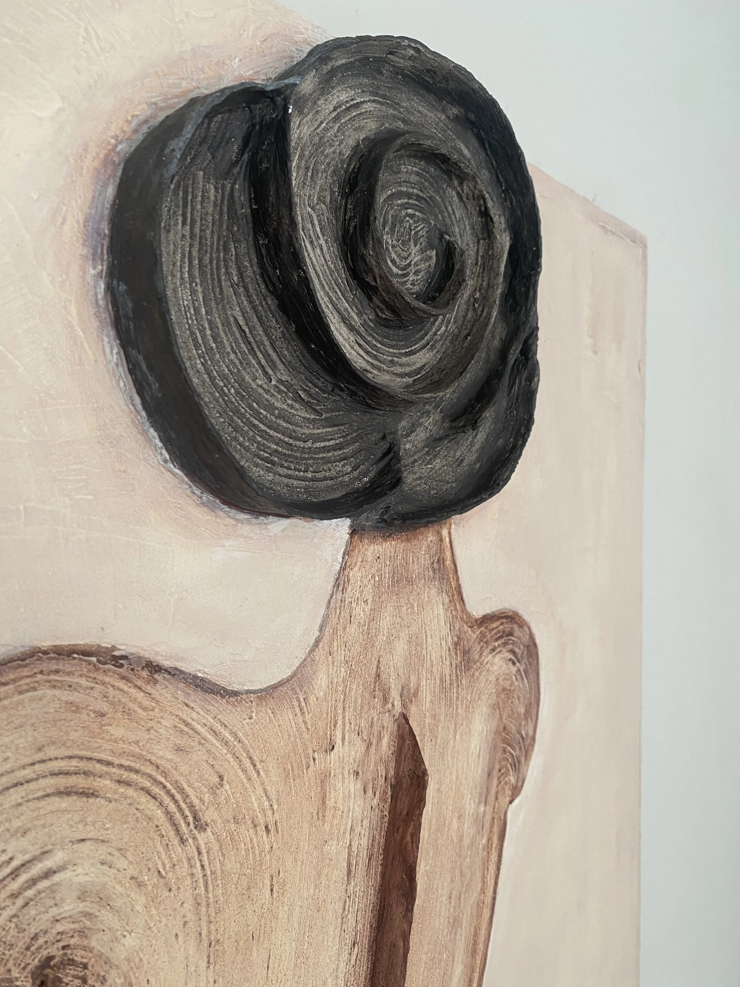 Close-up of a carved wooden sculpture depicting a person with dark, textured hair.