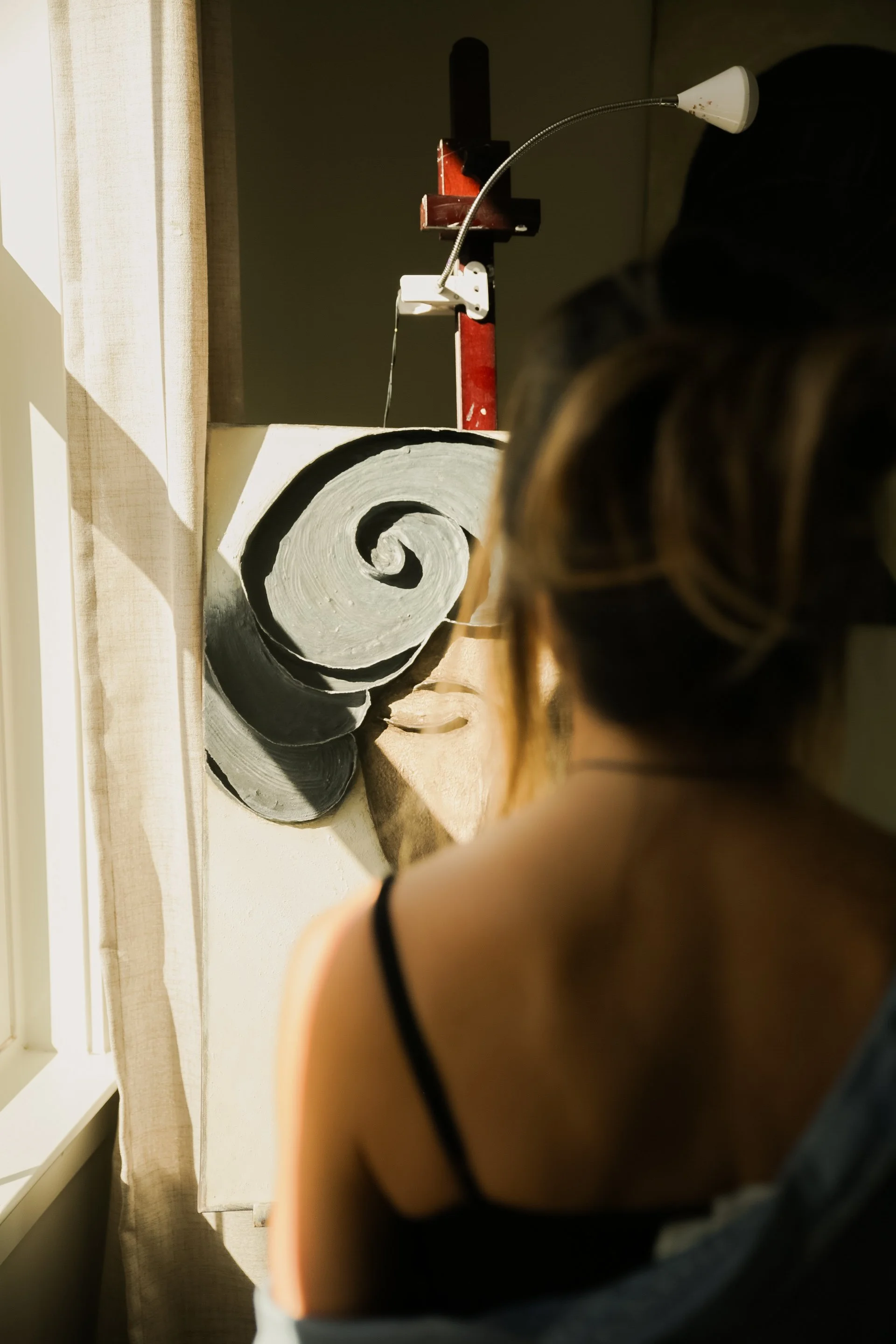 Person photographing a rolled canvas artwork beside a sunlit window