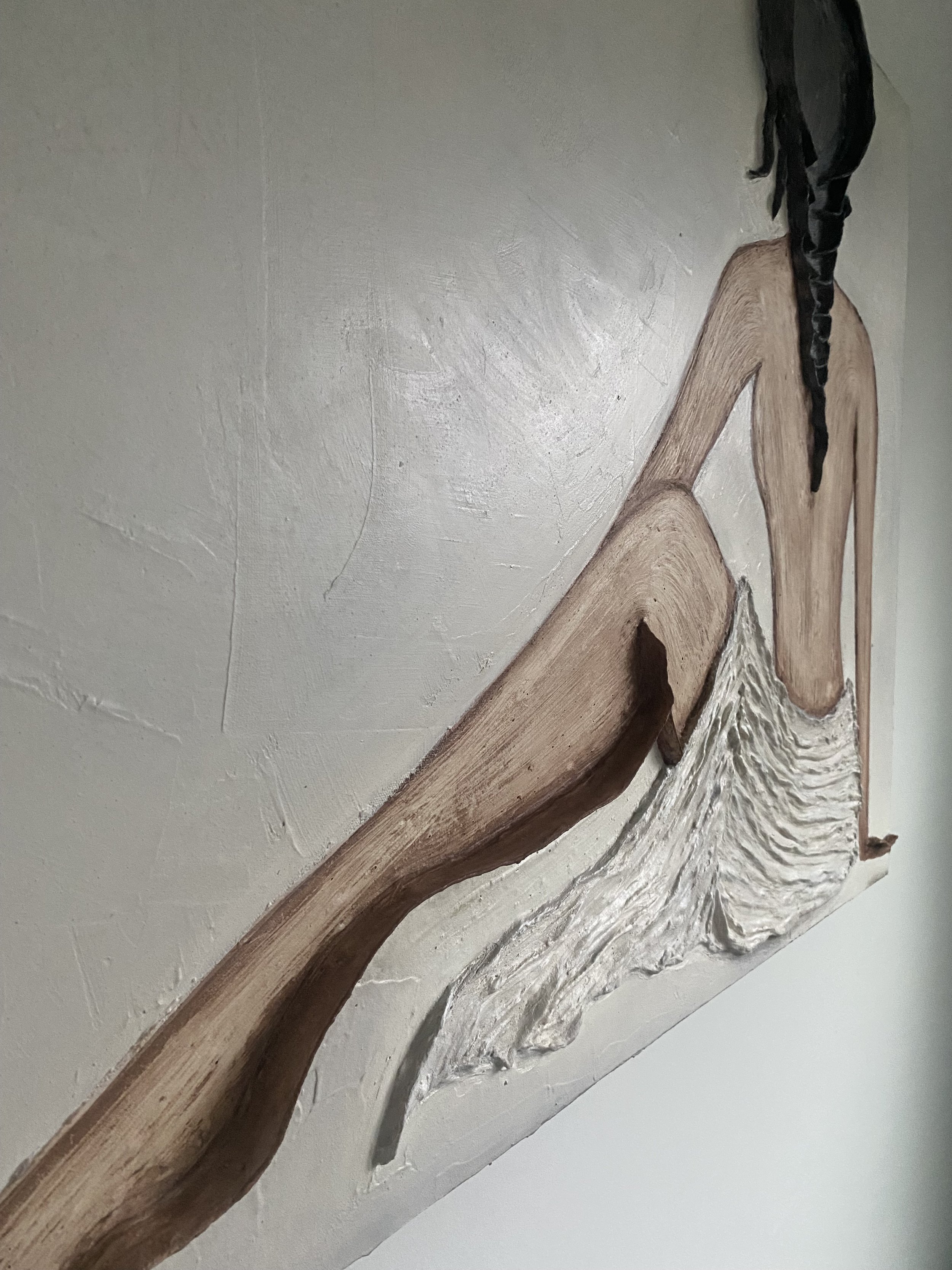 Close-up of rustic driftwood branches mounted on a textured white wall with black twine accents