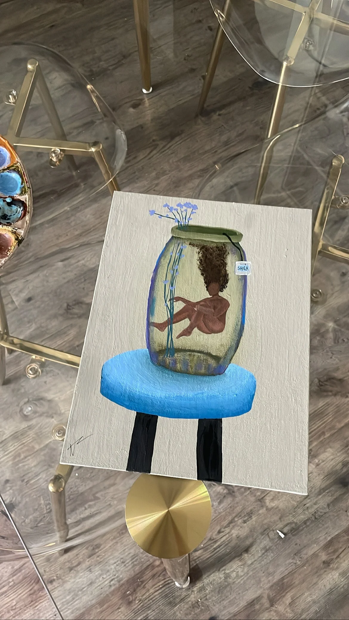 A painting of a nude woman depicted as a tea bag floating inside a glass jar with blue flowers and water, sitting on a blue cushion on a black stool.