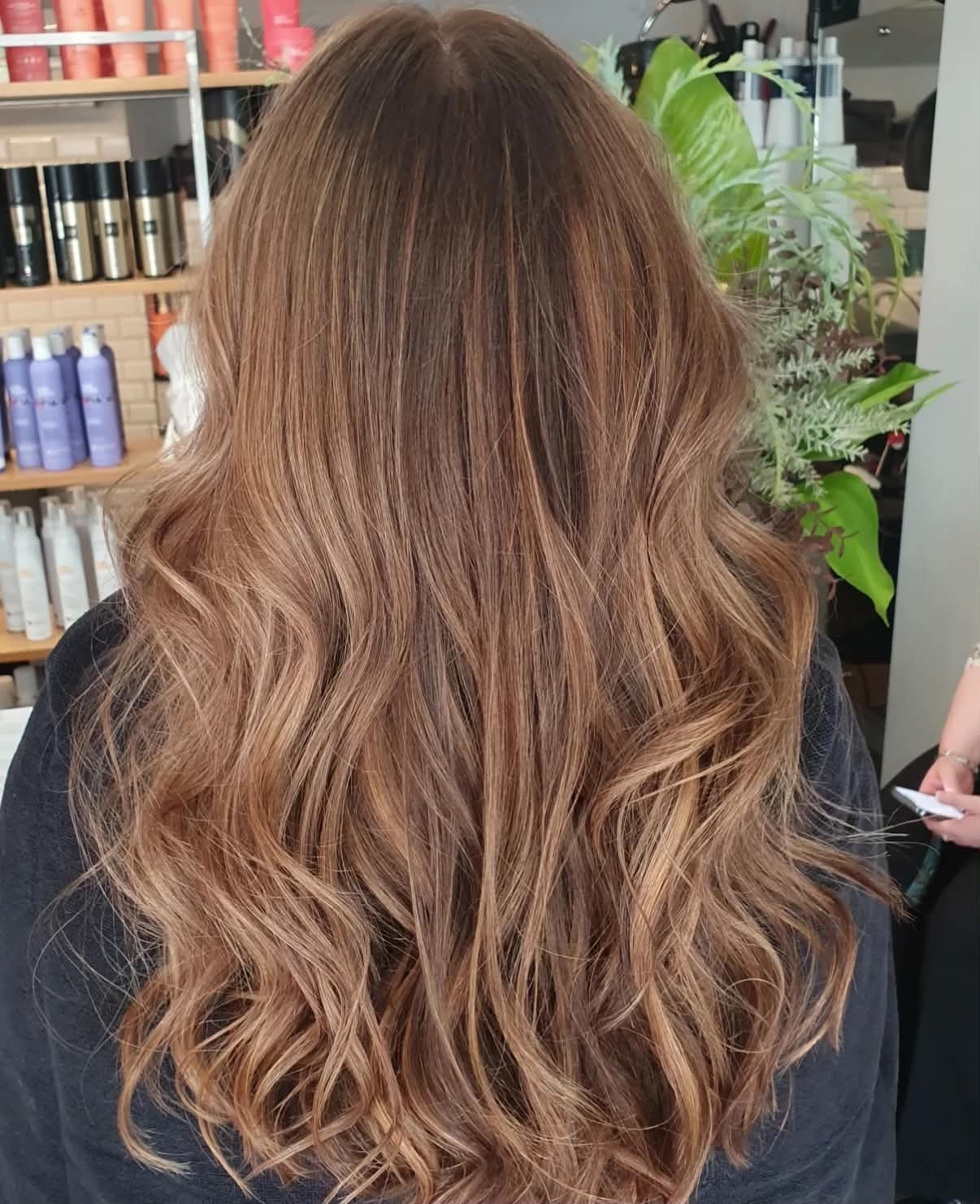 Back view of a woman with long, wavy, light brown hair.