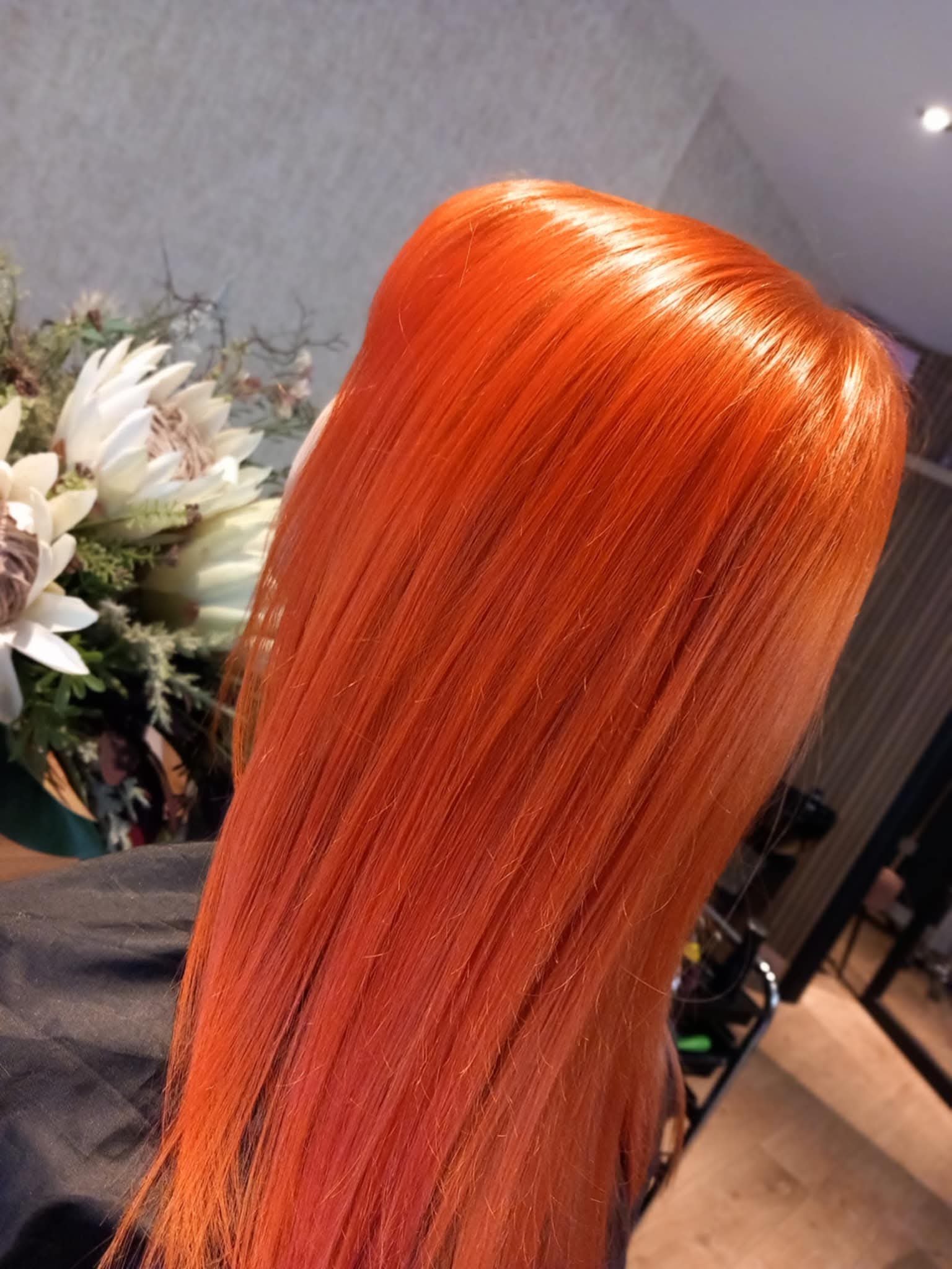 Close-up of bright orange, straight, shiny hair on a mannequin or person.