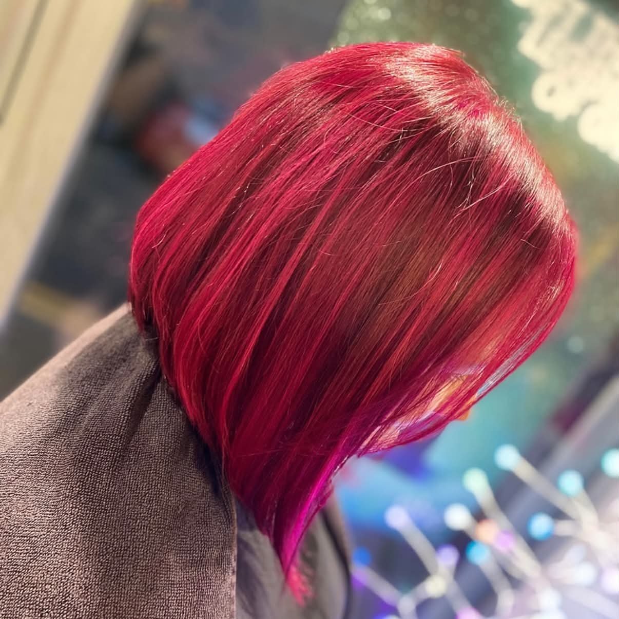 Back of a person's head with bright pink and red colored straight hair.