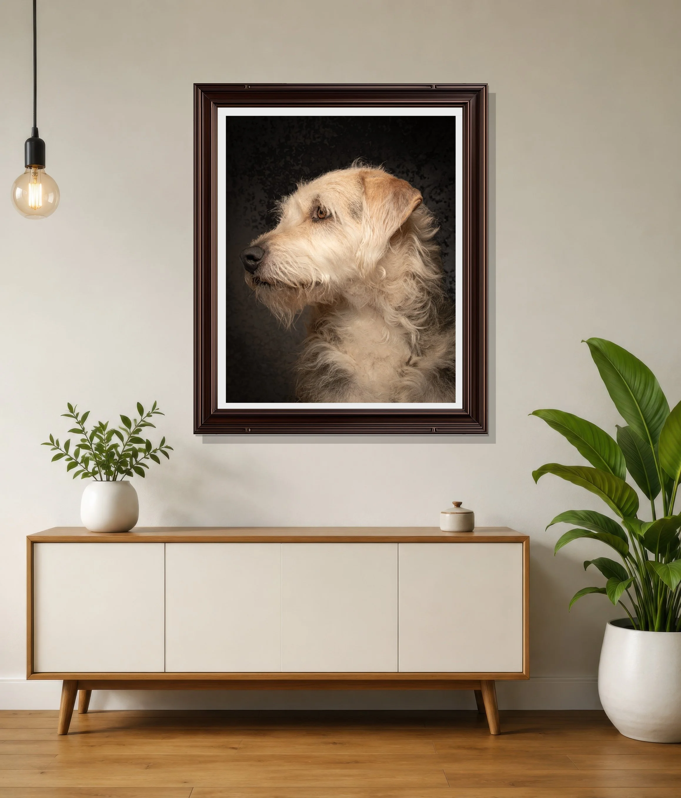 Modern living room with a minimalist white sideboard, a large framed portrait of a dog on the wall, potted green plants, and a wooden floor illuminated by a hanging Edison-style light bulb.