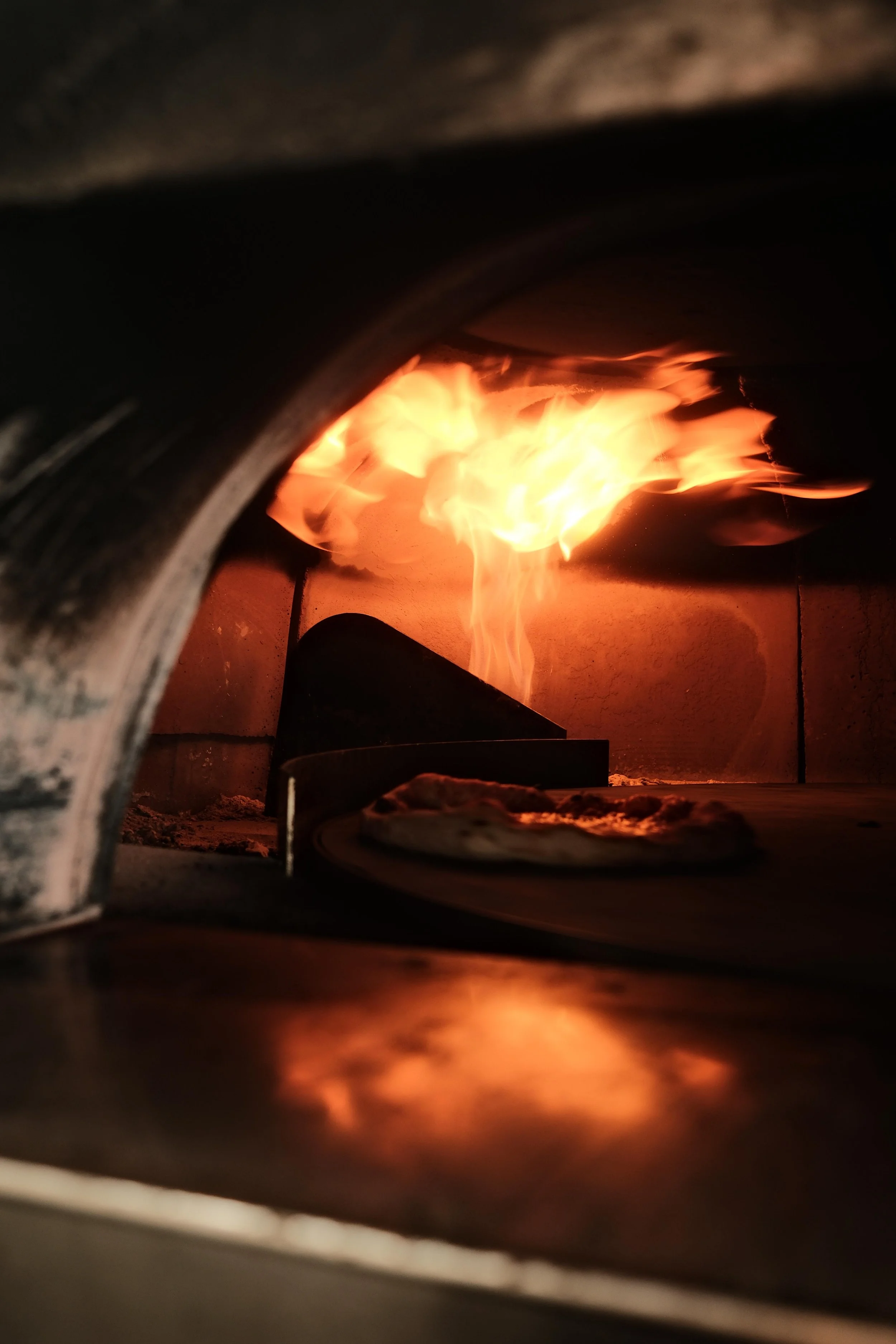 Horecafotografie van een houtoven tijdens de bereiding van pizza, onderdeel van een restaurantshoot door De Eetgency met focus op keuken, bereiding en sfeer