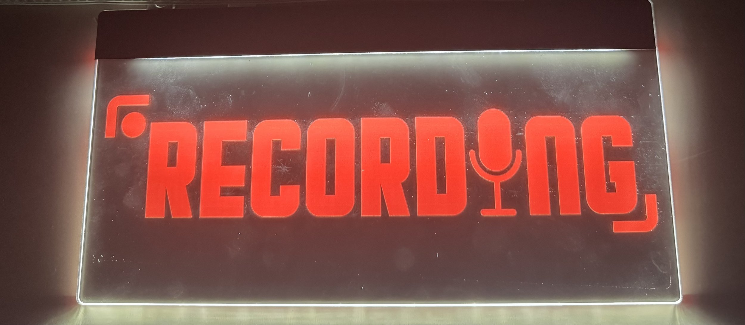 A sign with illuminated red letters spelling 'RECOLOGY' on a metallic background.
