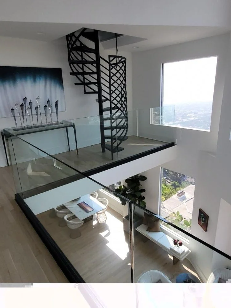 Architectural loft interior buildout with custom black steel spiral staircase and glass railings by Big City Construction
