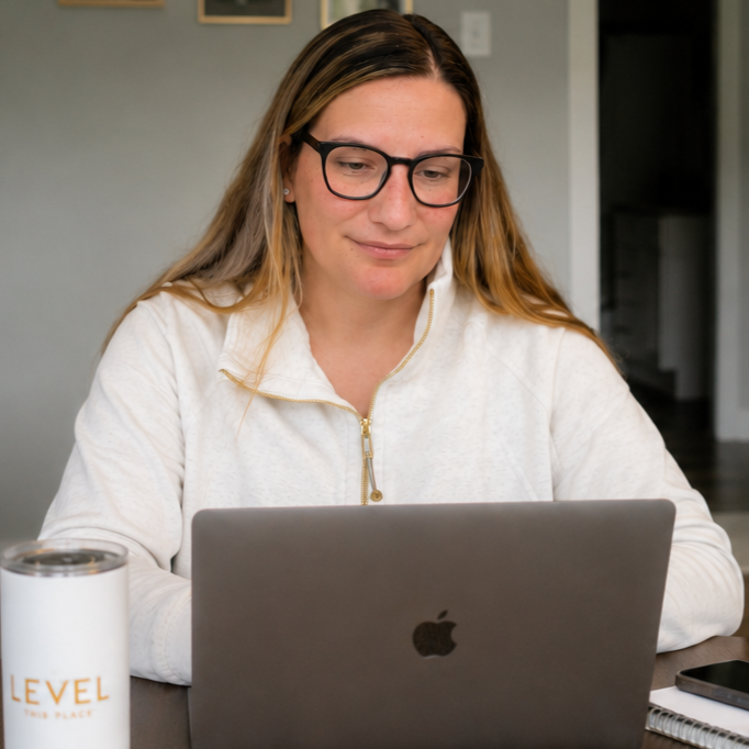 Woman with glasses working on a laptop at a desk.