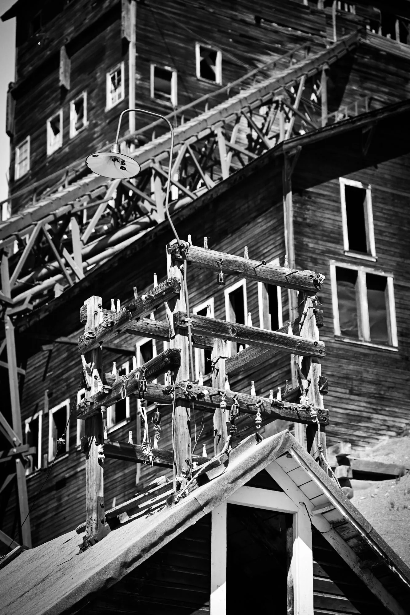 Black and white photo of a wooden house under construction with scaffolding and a ladder in front.