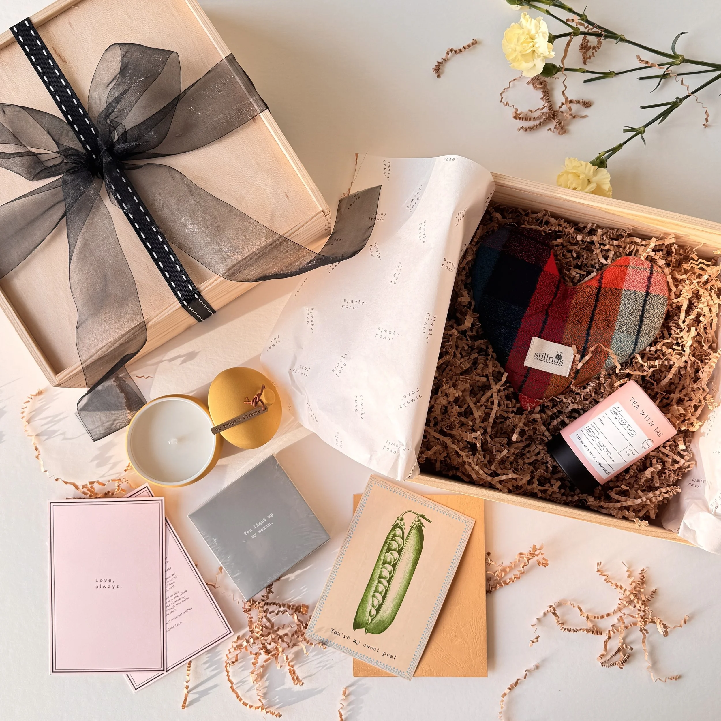 Two Go Gaga Gifts boxes styled side by side, one wrapped in black organza ribbon and one open mid-curation.