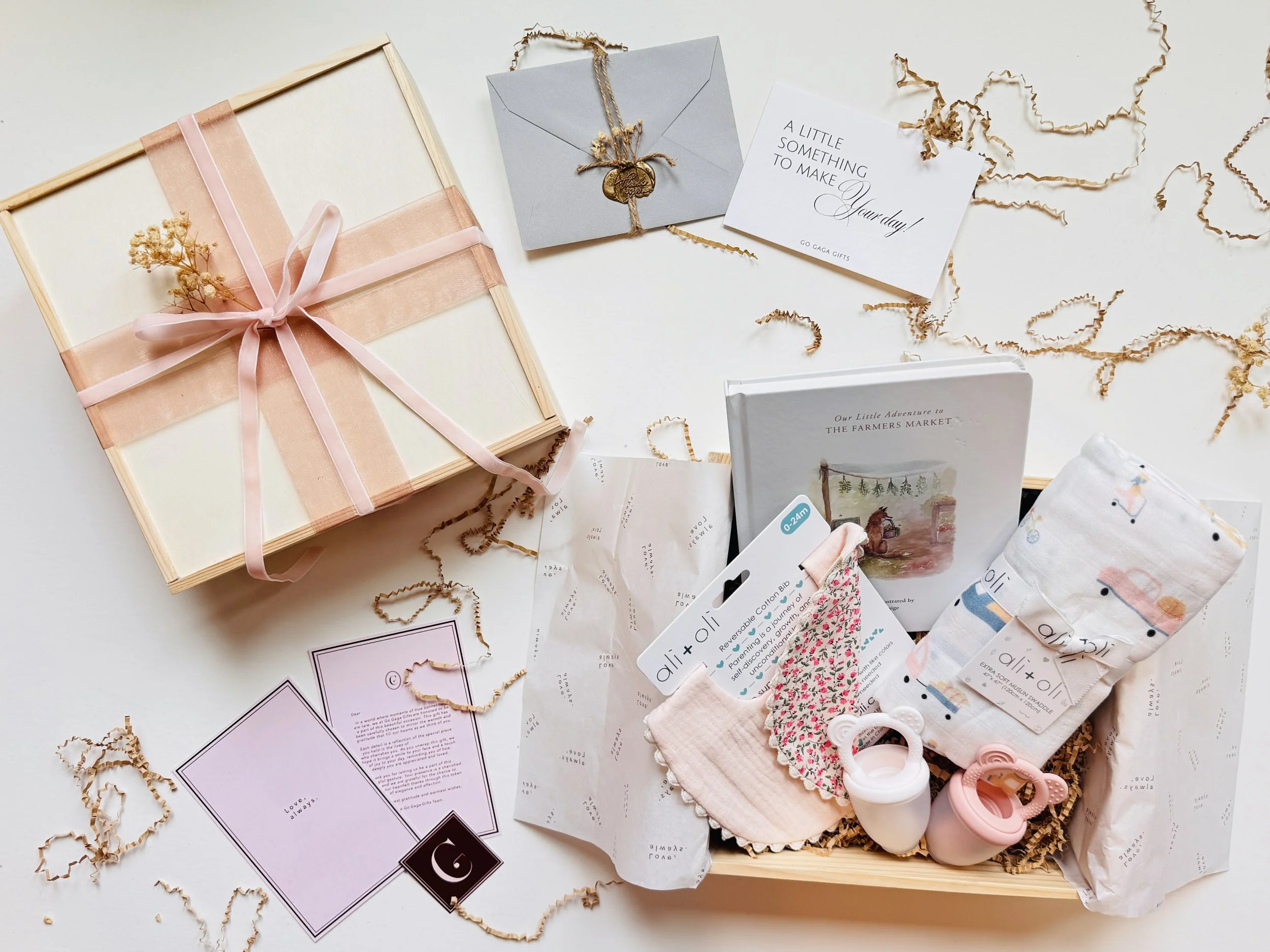 Welcome Little One luxury baby gift box with muslin swaddle, cotton bibs, storybook, and blush pink ribbon by Go Gaga Gifts