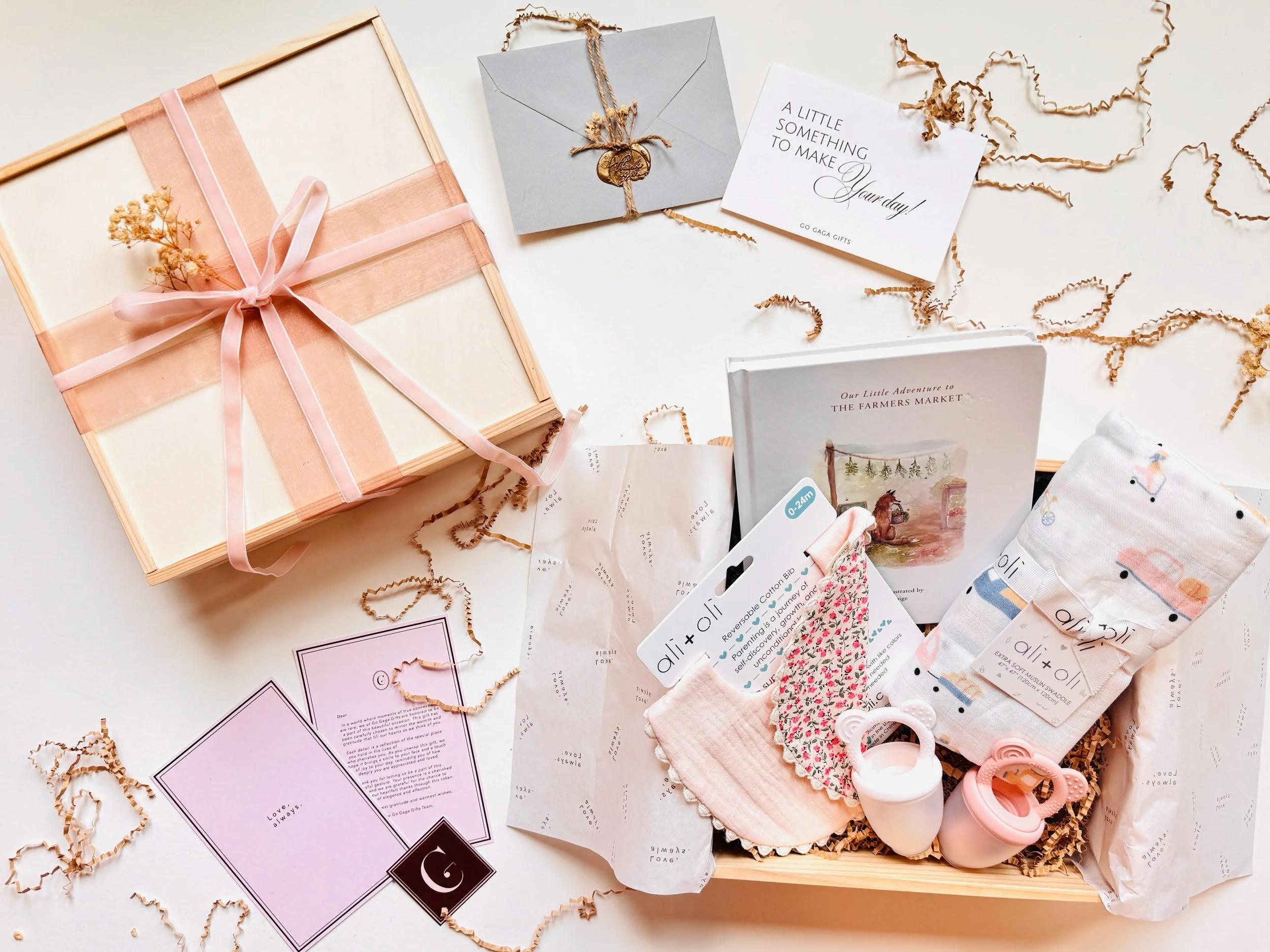 Welcome Little One luxury baby gift box with bamboo muslin swaddle, organic cotton bibs, fruit feeders, storybook, and keepsakes in a wooden box with ribbon