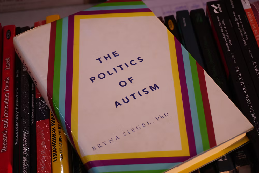 A book titled "The Politics of Autism" by Bryna Siegel PhD resting on a shelf among other books.