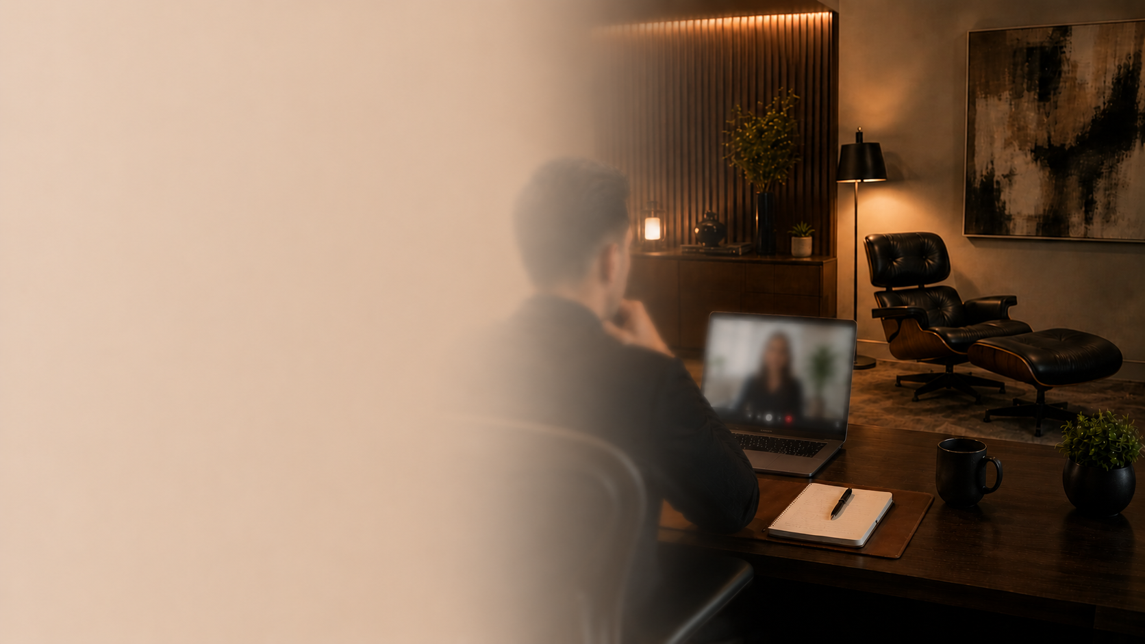 A person sitting at a desk in a modern, dimly lit room with a laptop, notebook, pen, black mug, and small potted plants. Private telepsychiatry consultation in a modern, welcoming psychiatric office