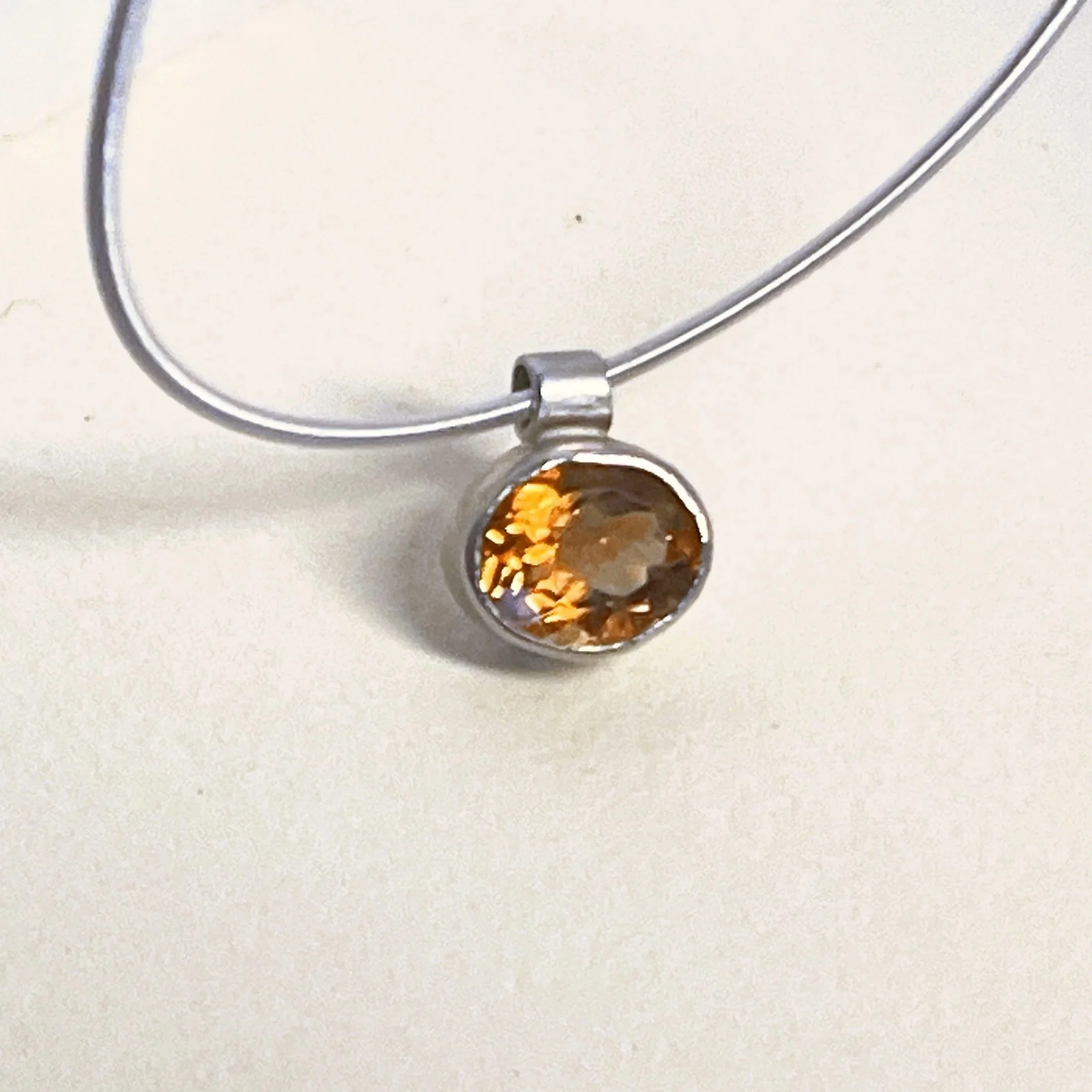 Single stone necklace — faceted orange citrine on a silver coil choker.  
Choker 16 in · stone 9x11mm