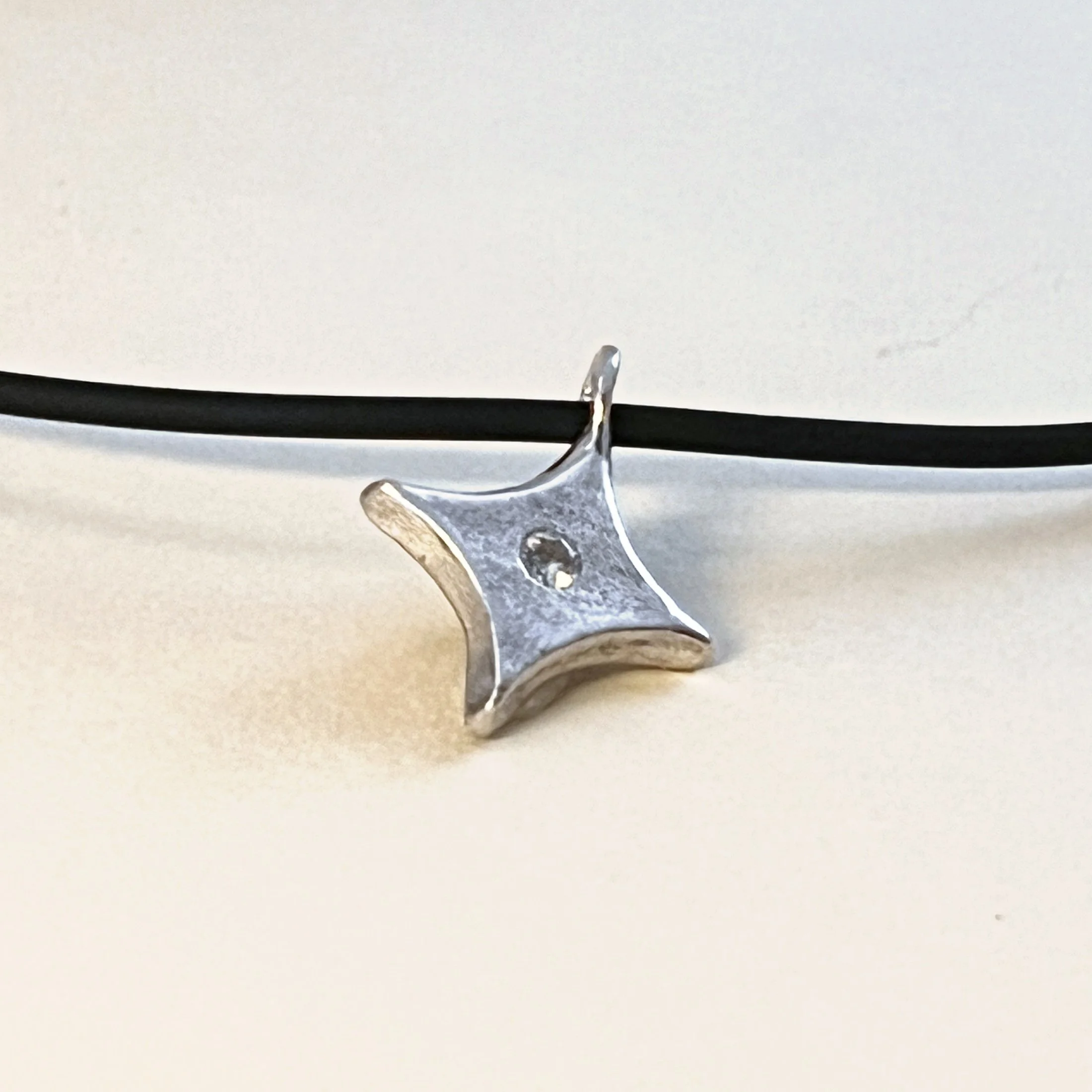 Star pendant — cubic zirconia in sterling silver, on a black cord.
Cord 15in · pendant 17x17mm