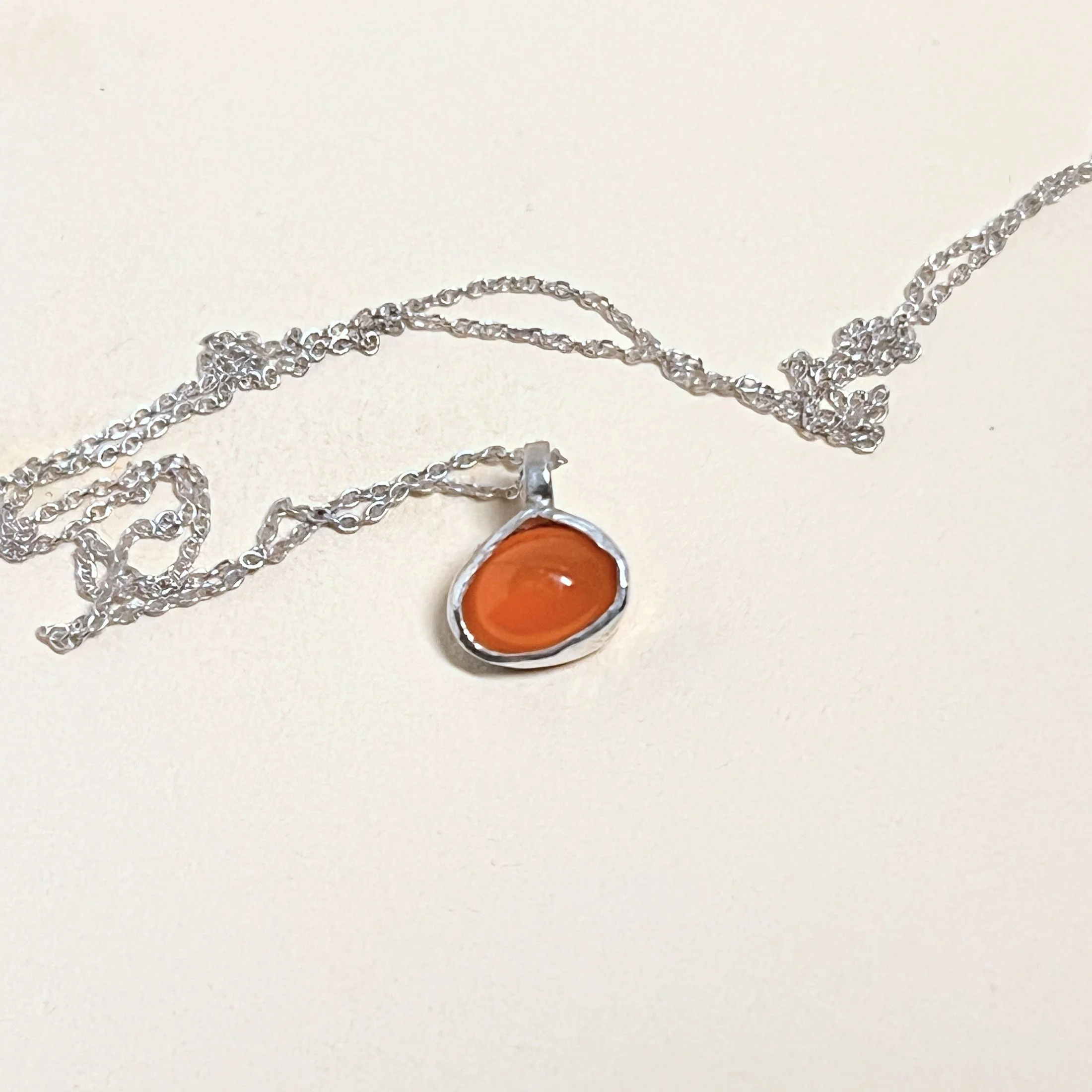 Pendant — orange chalcedony cabochon on a fine sterling silver chain.
Chain 16in · pendant 7x10mm
