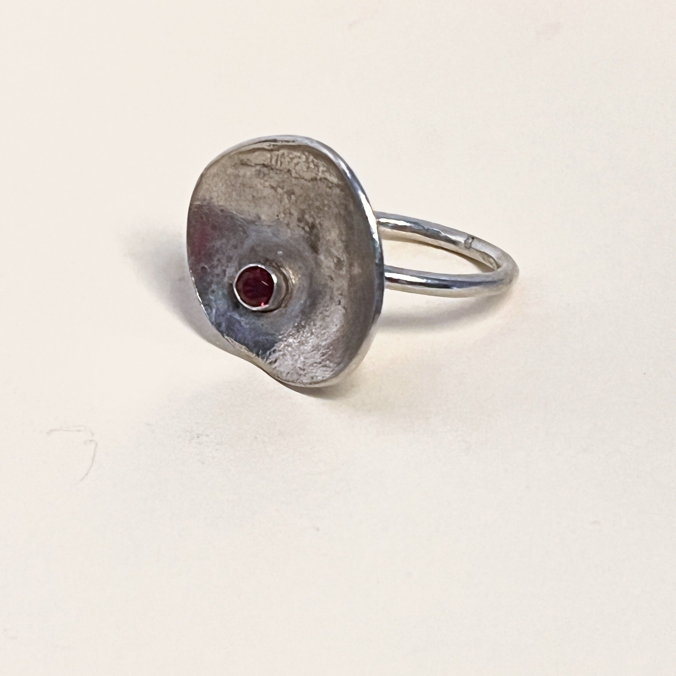Ring — garnet set into a hand-melted sterling silver disc.
Band 1.5mm · thickness 1.5mm · disc 21mm · stone 3.5mm
