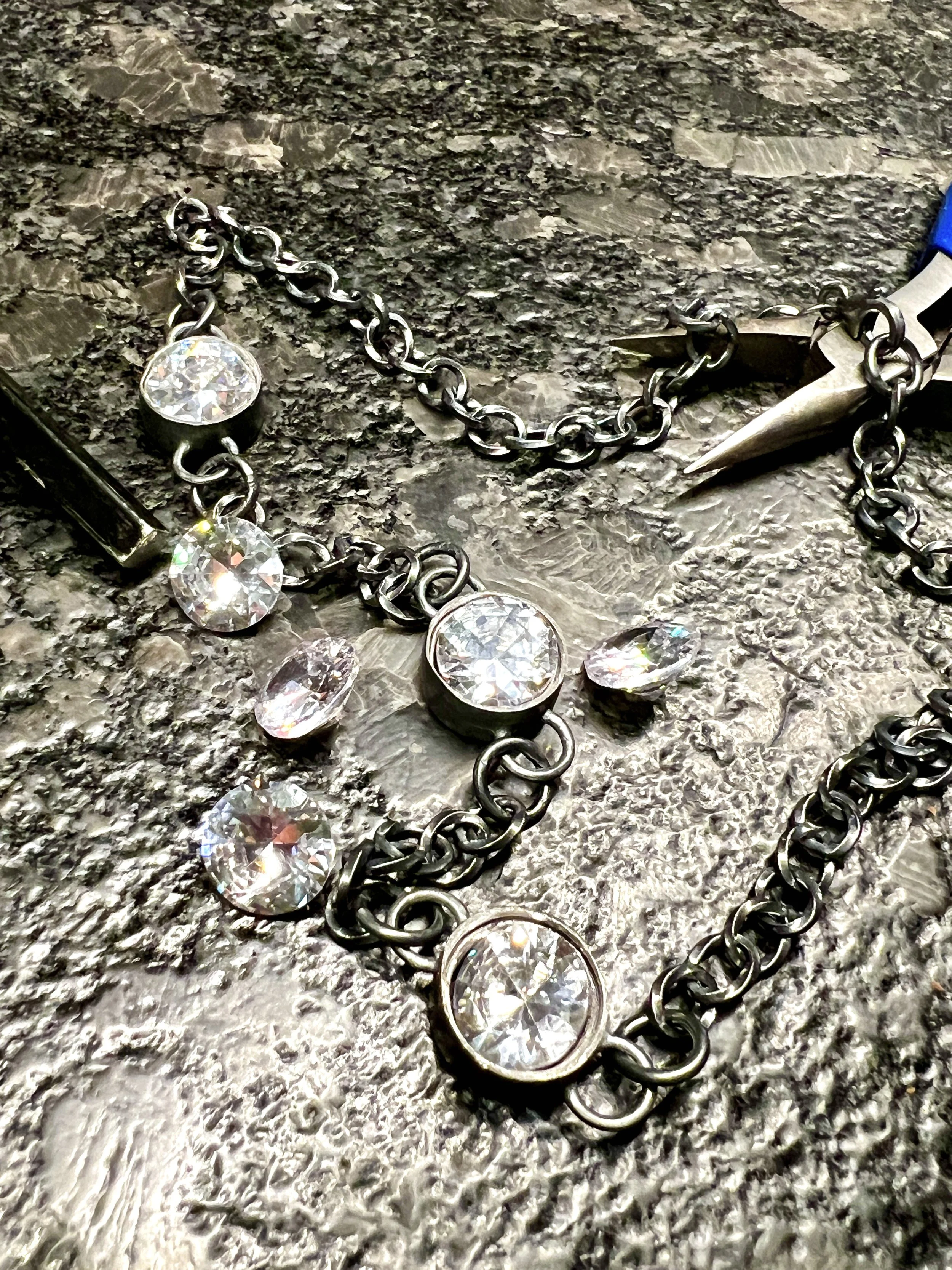 Jewelers pliers and cubic zirconia stones on the workbench