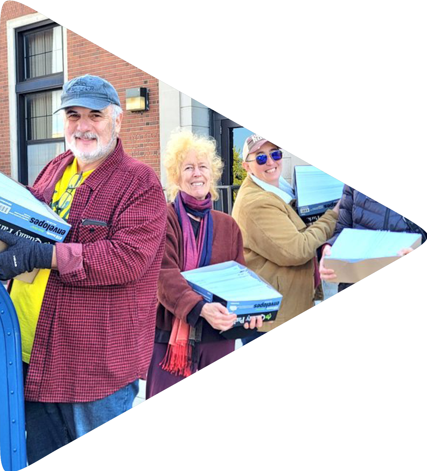 A group of people holding boxes of letters outside a post office.