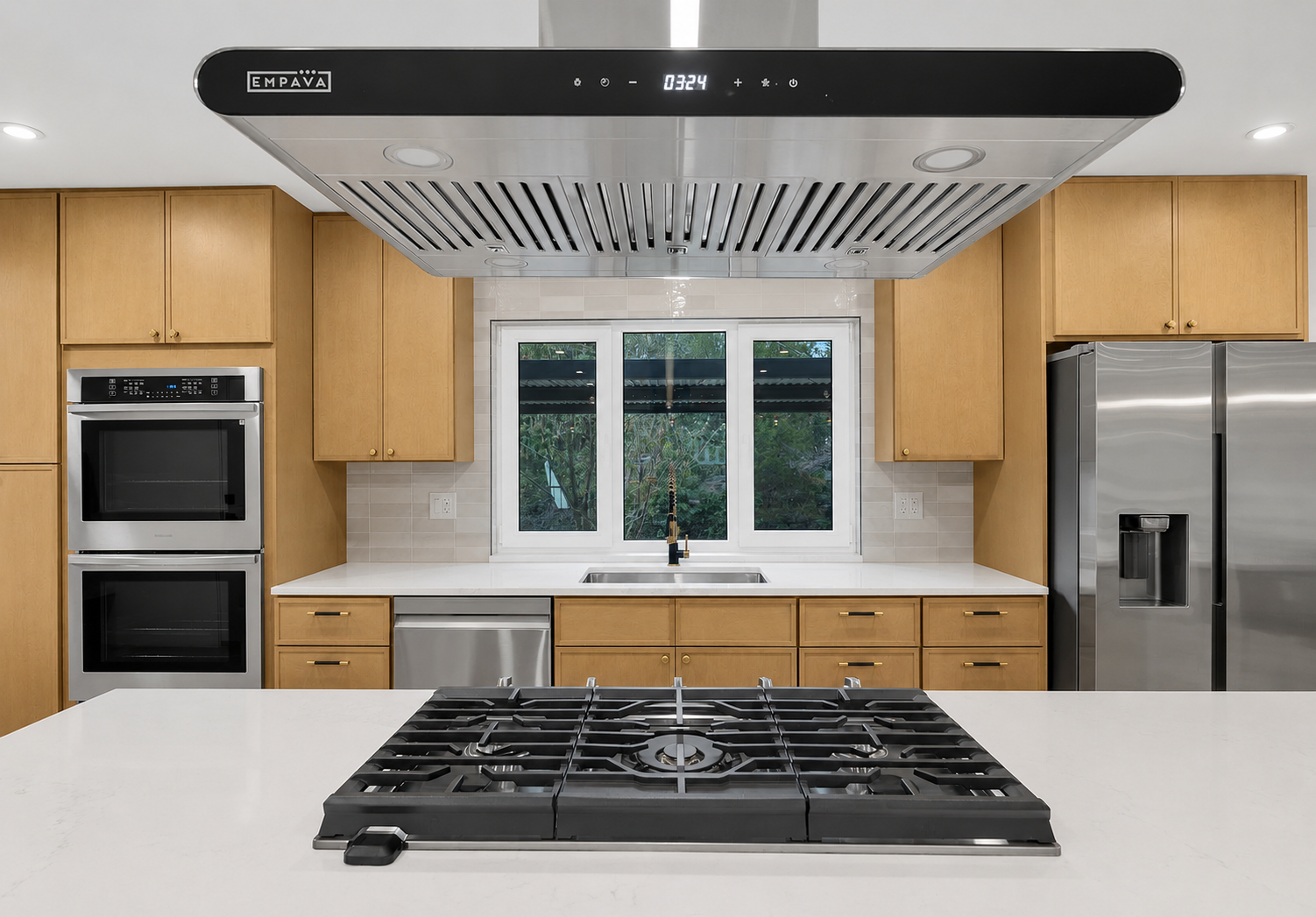 Modern kitchen with wooden cabinets, stainless steel appliances, a stove on a white island, a window above the sink, and a large stainless steel refrigerator.