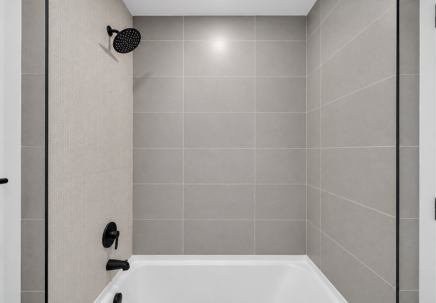 Empty modern shower with gray tiles, black showerhead, and black fixtures.
