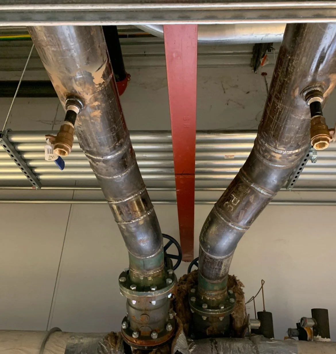 Two large industrial pipes connected to a metal structure with flanges and bolts, in an industrial setting.