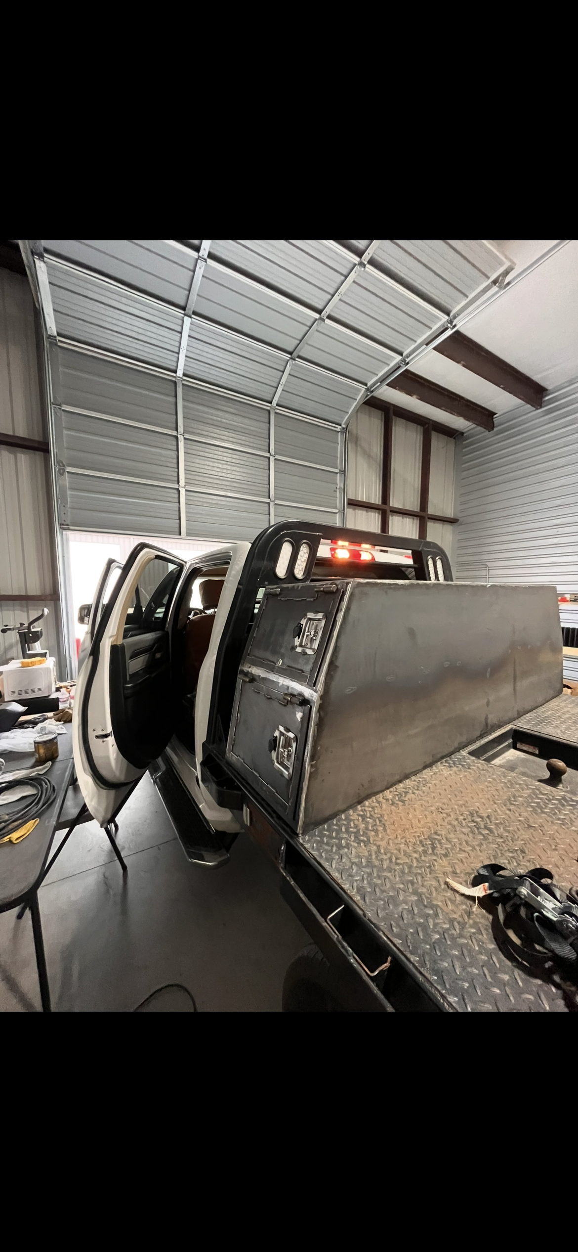 A pickup truck with a flatbed in a workshop garage, with various tools and equipment around.