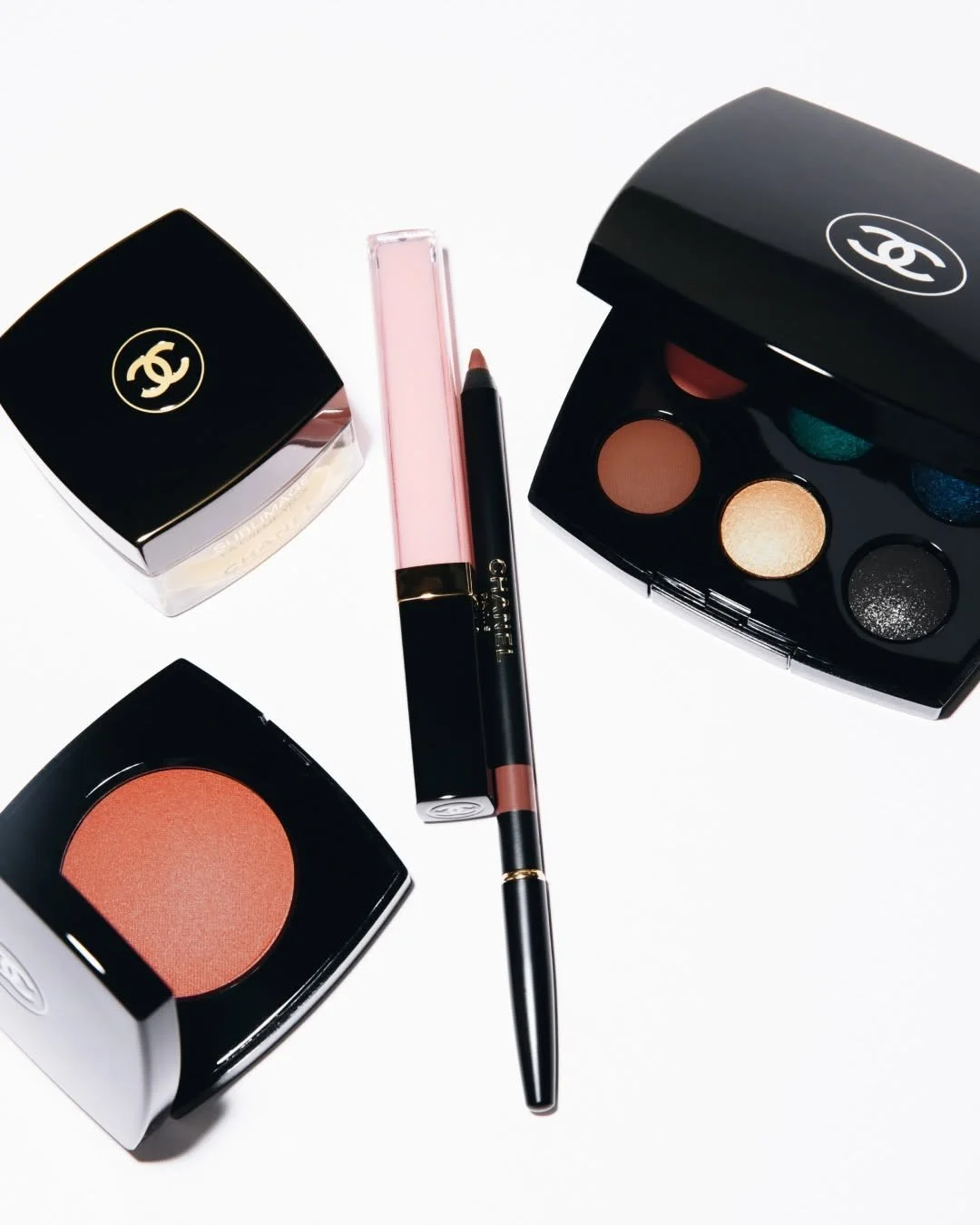 Collection of Chanel makeup products including eyeshadow palettes and blushes on a white background.