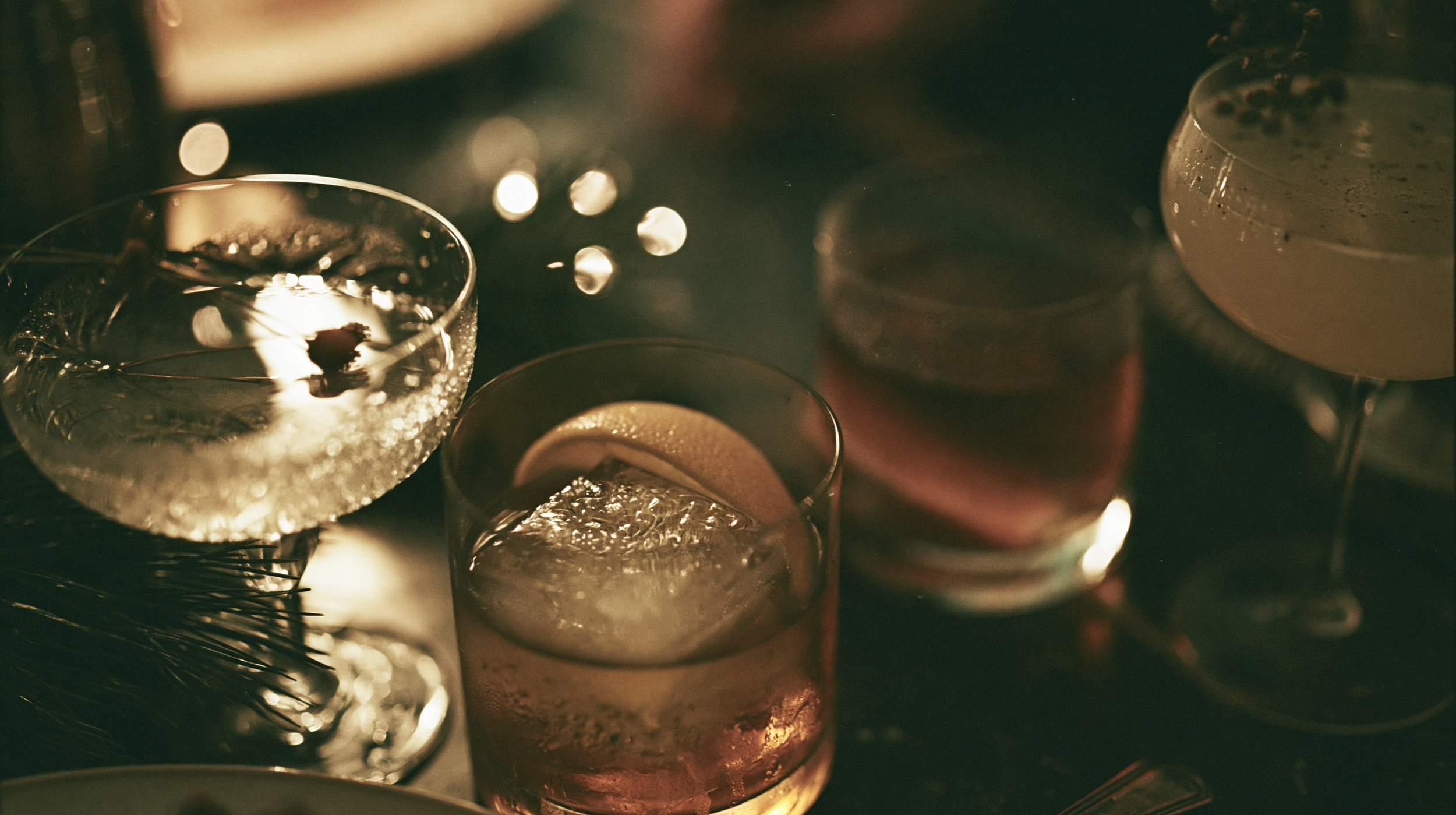Multiple glasses of champagne with condensation on the outside, placed together on a dark surface in a warm, dimly lit setting.
