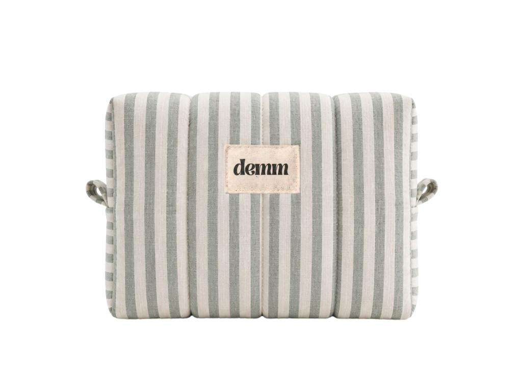 A handmade green striped quilted make up bag with the brand name 'DEMM'.