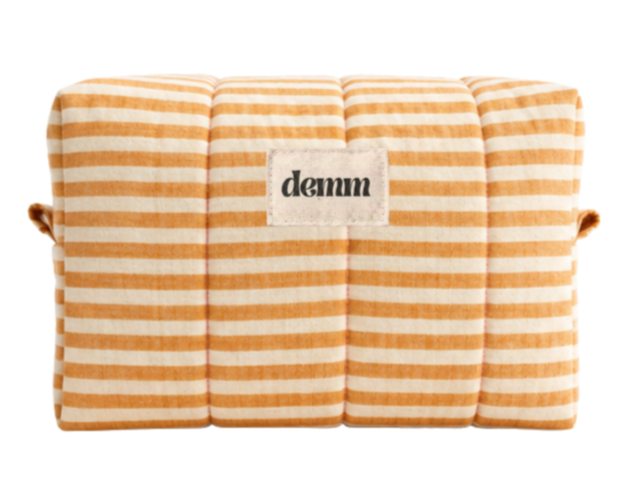 A handmade yellow striped quilted make up bag with the brand name 'DEMM'.