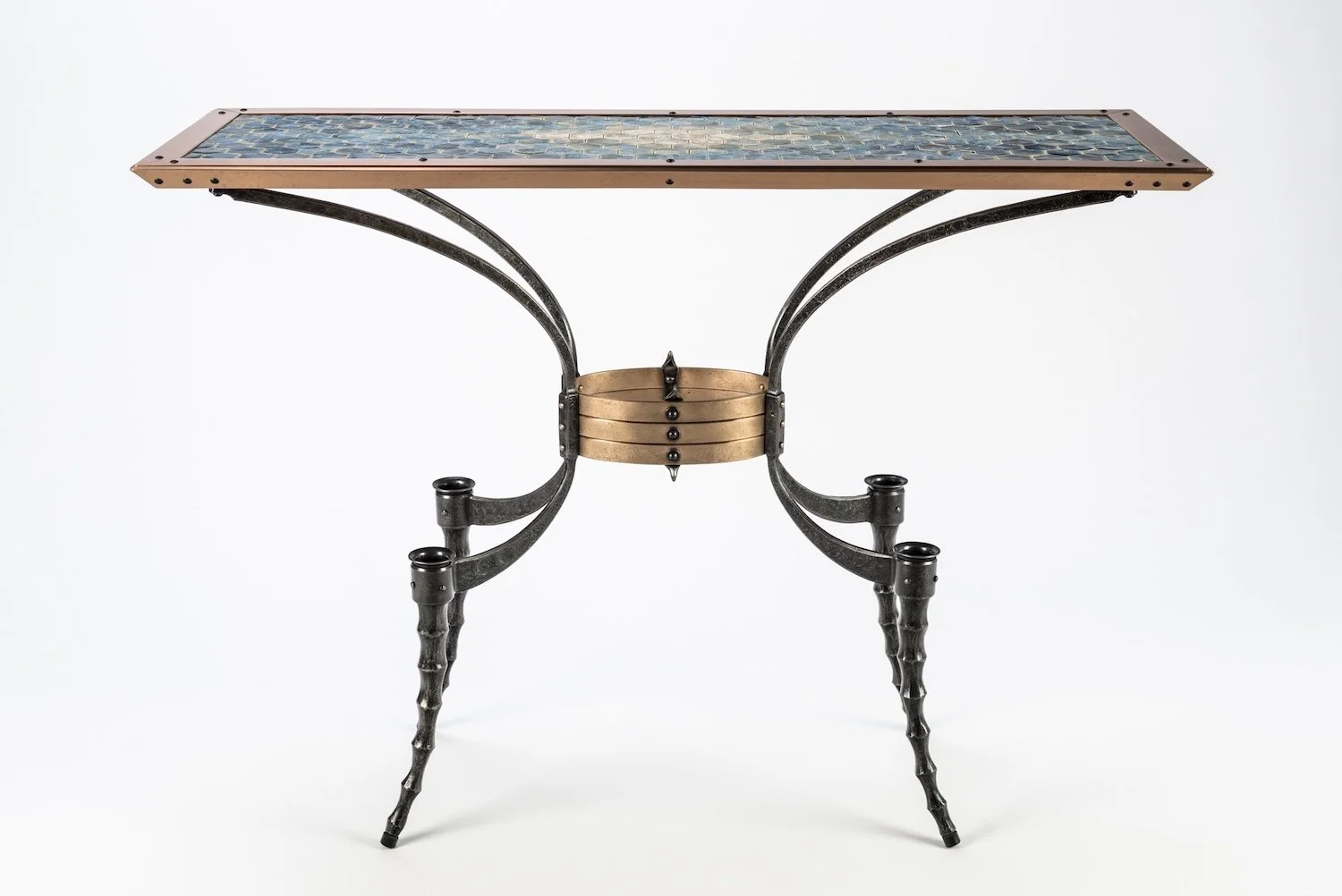 A table with a mosaic glass top, metal legs, and a circular decorative element at the center.