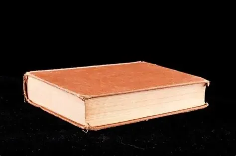 A closed hardcover book with a reddish-brown cover placed on a black background.
